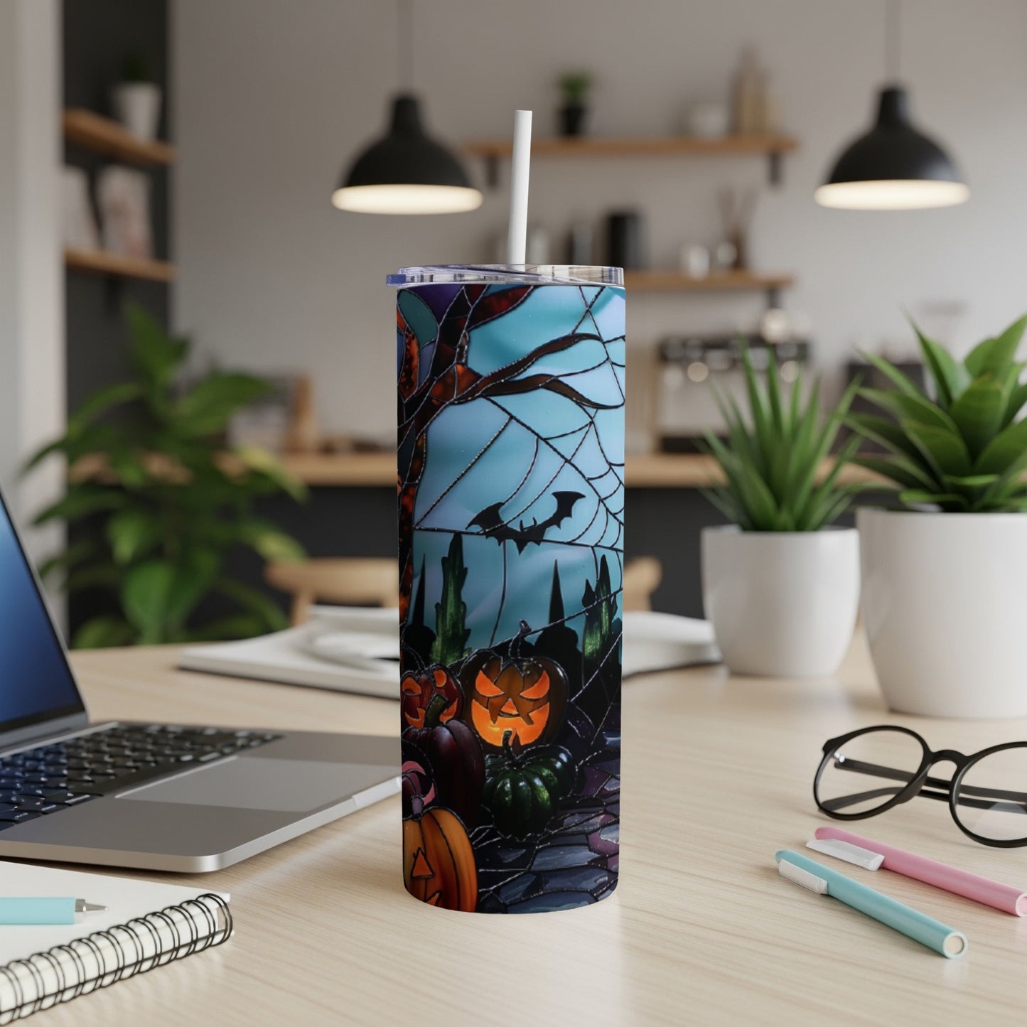 Halloween tumbler with pumpkins, bats, and spiderwebs on a desk.