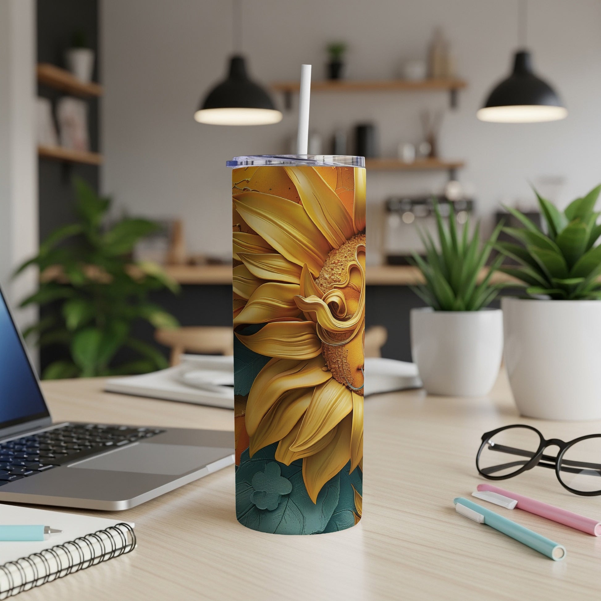 Tall tumbler with sunflower design on a desk next to a laptop.