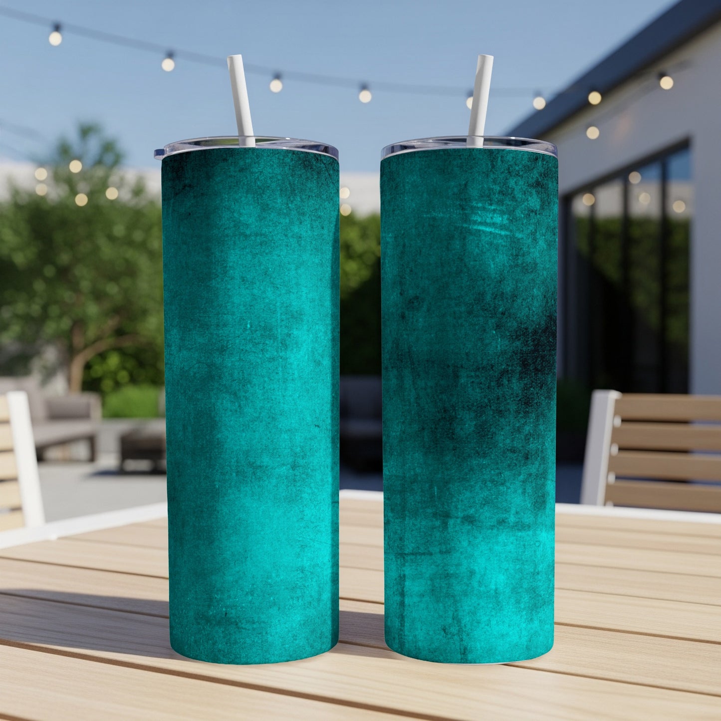 Two cyan textured tumblers with white straws on a wooden table outdoors.