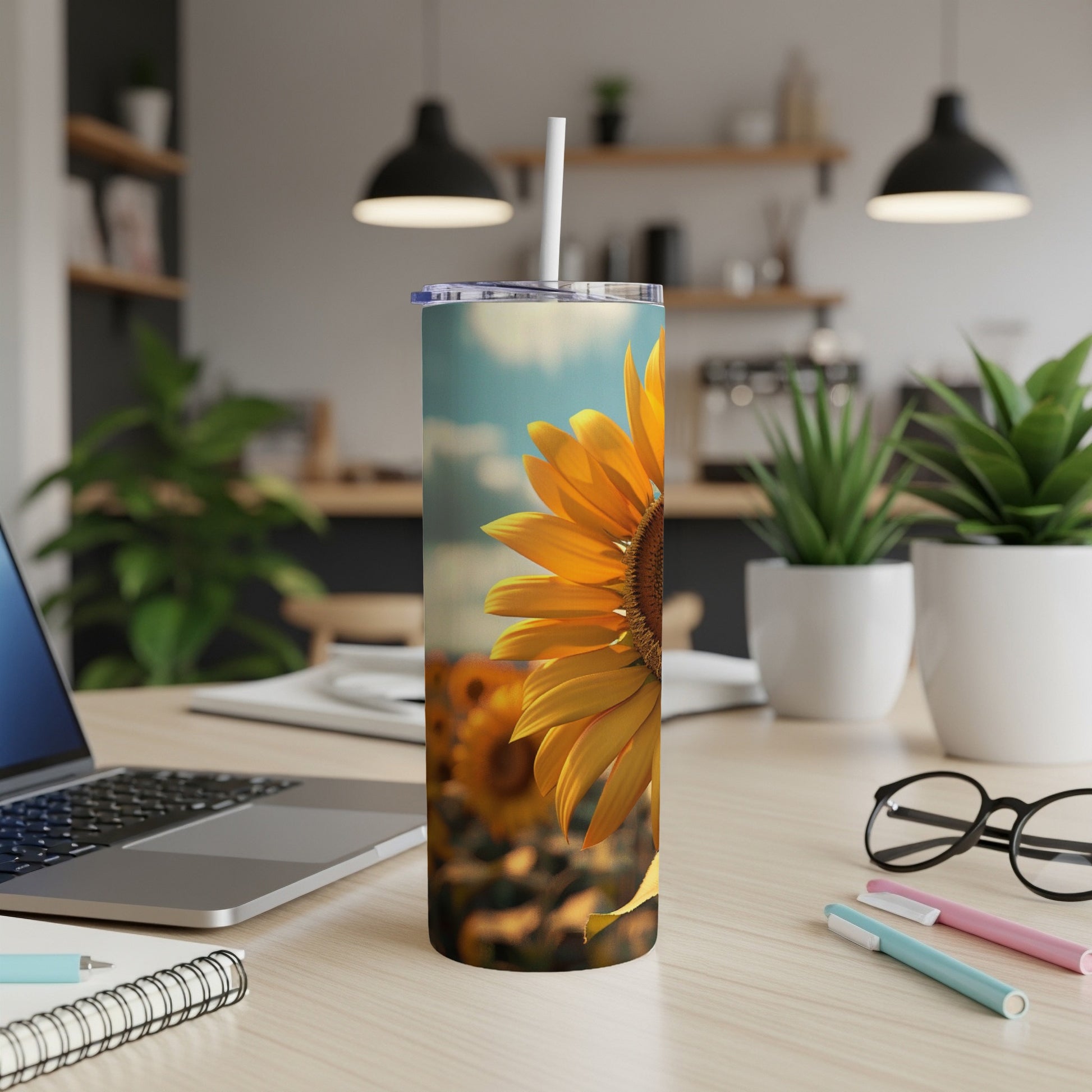 Close-up of a sunflower on a travel tumbler with a desk and plants in the background.
