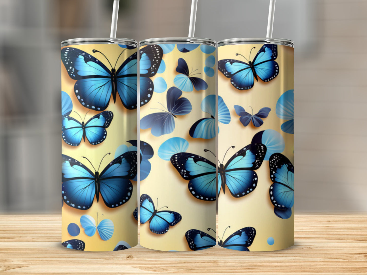 Three tumblers with blue butterfly designs on a light yellow background.