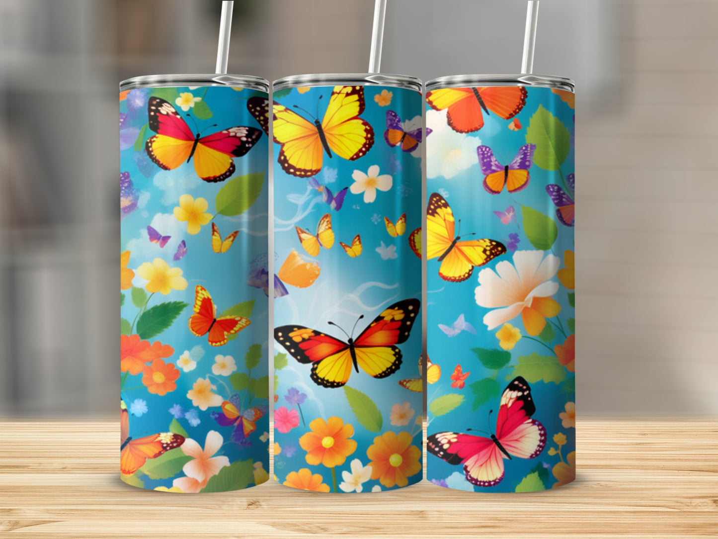 Three tumblers with colorful butterflies and flowers on a wooden surface.