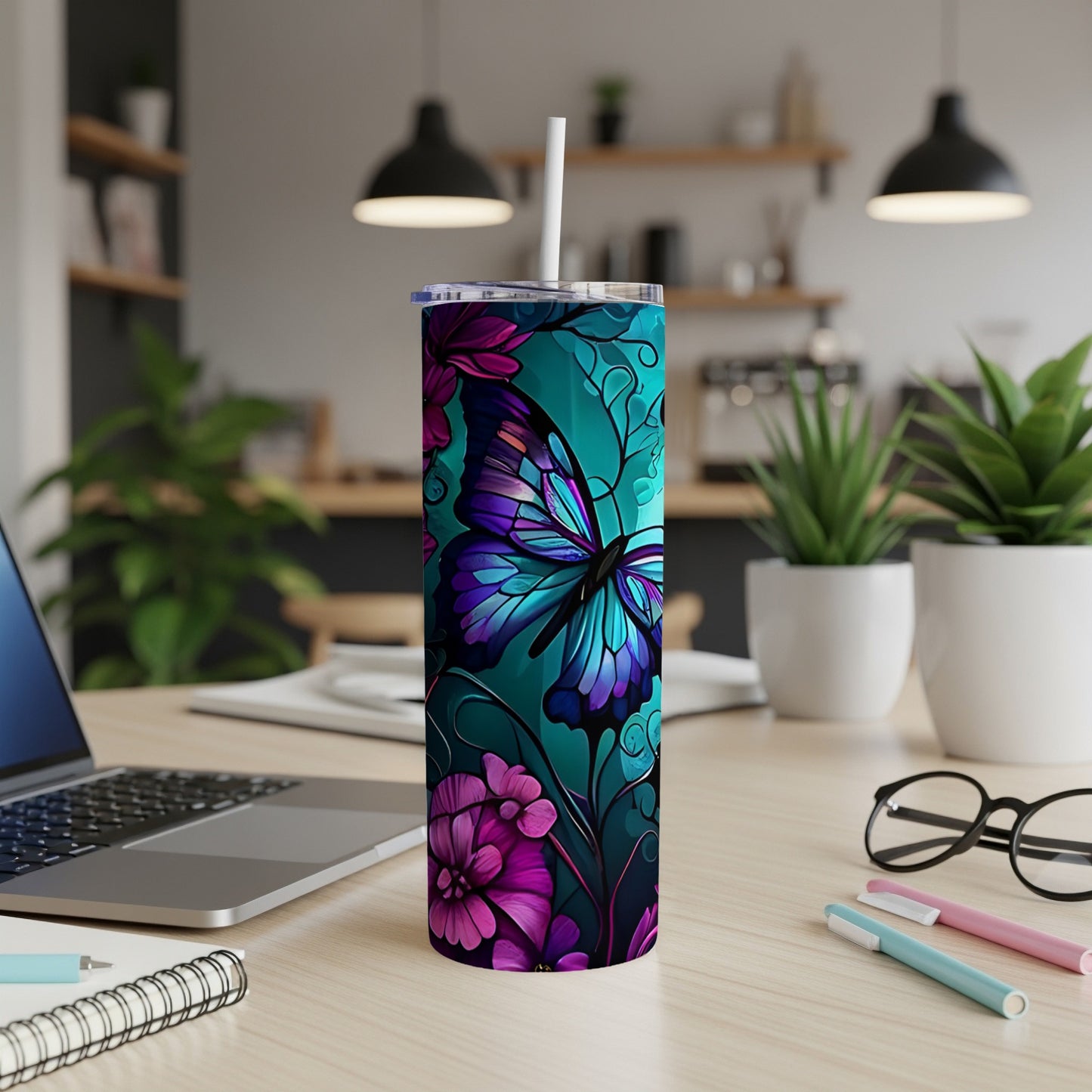 Turquoise tumbler with a butterfly and floral design, straw inserted.