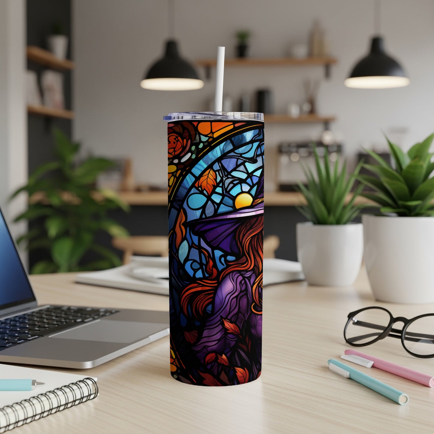 Stained glass tumbler with witch and moon design on a desk.