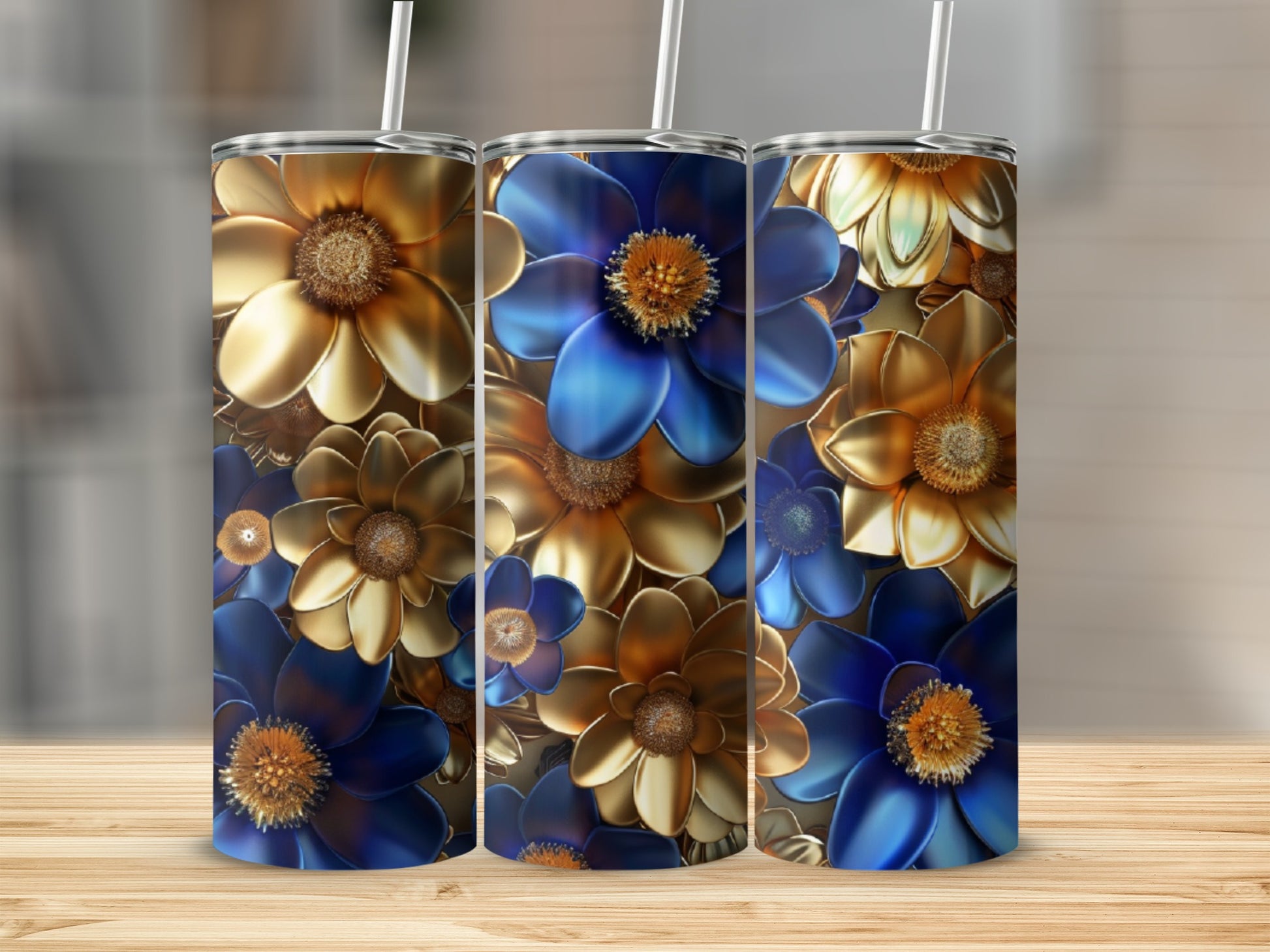 Three golden and blue metallic floral pattern tumblers on a wooden surface.