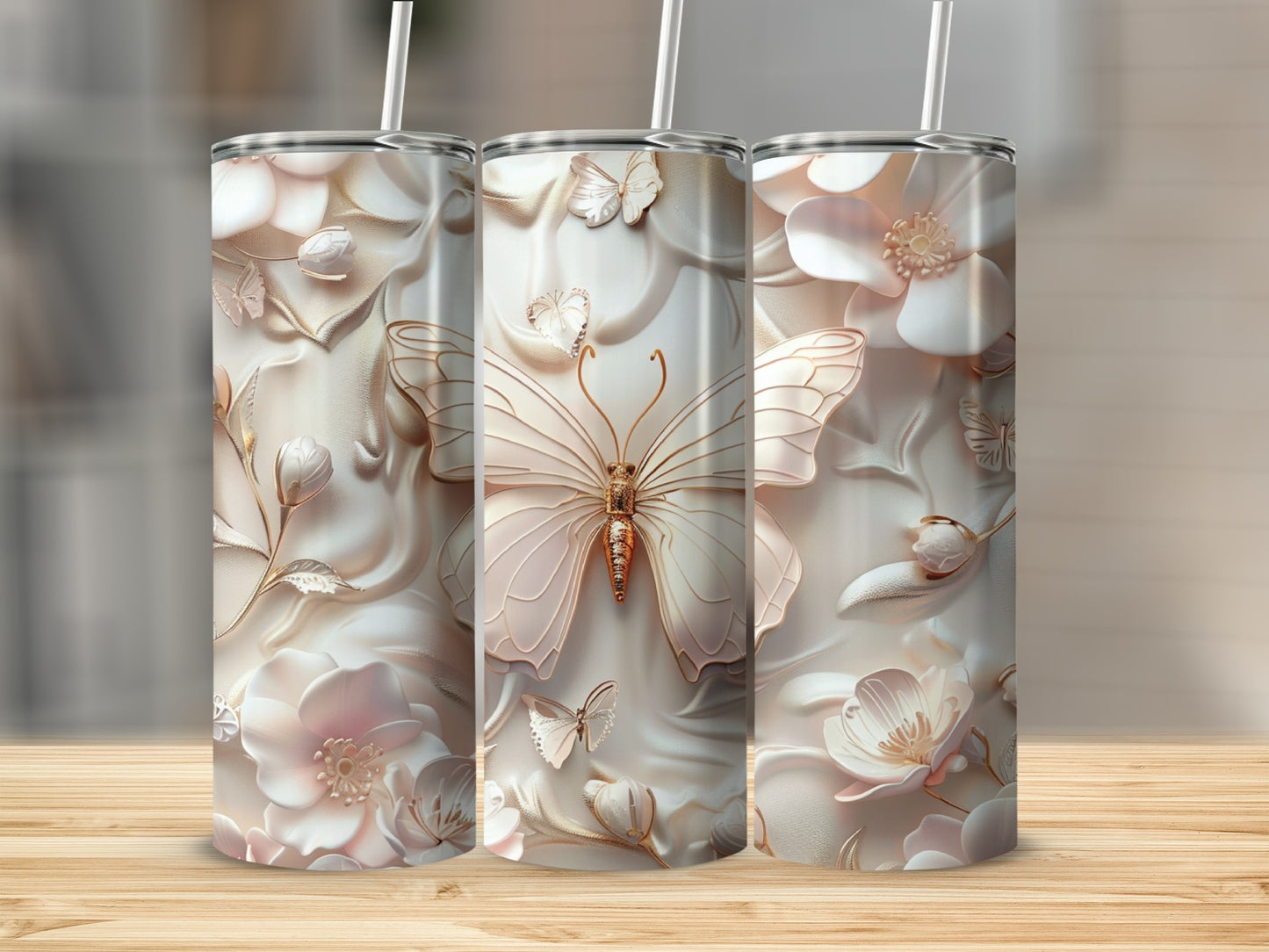 Three tall tumblers with embossed butterflies and flowers, on a wooden surface.
