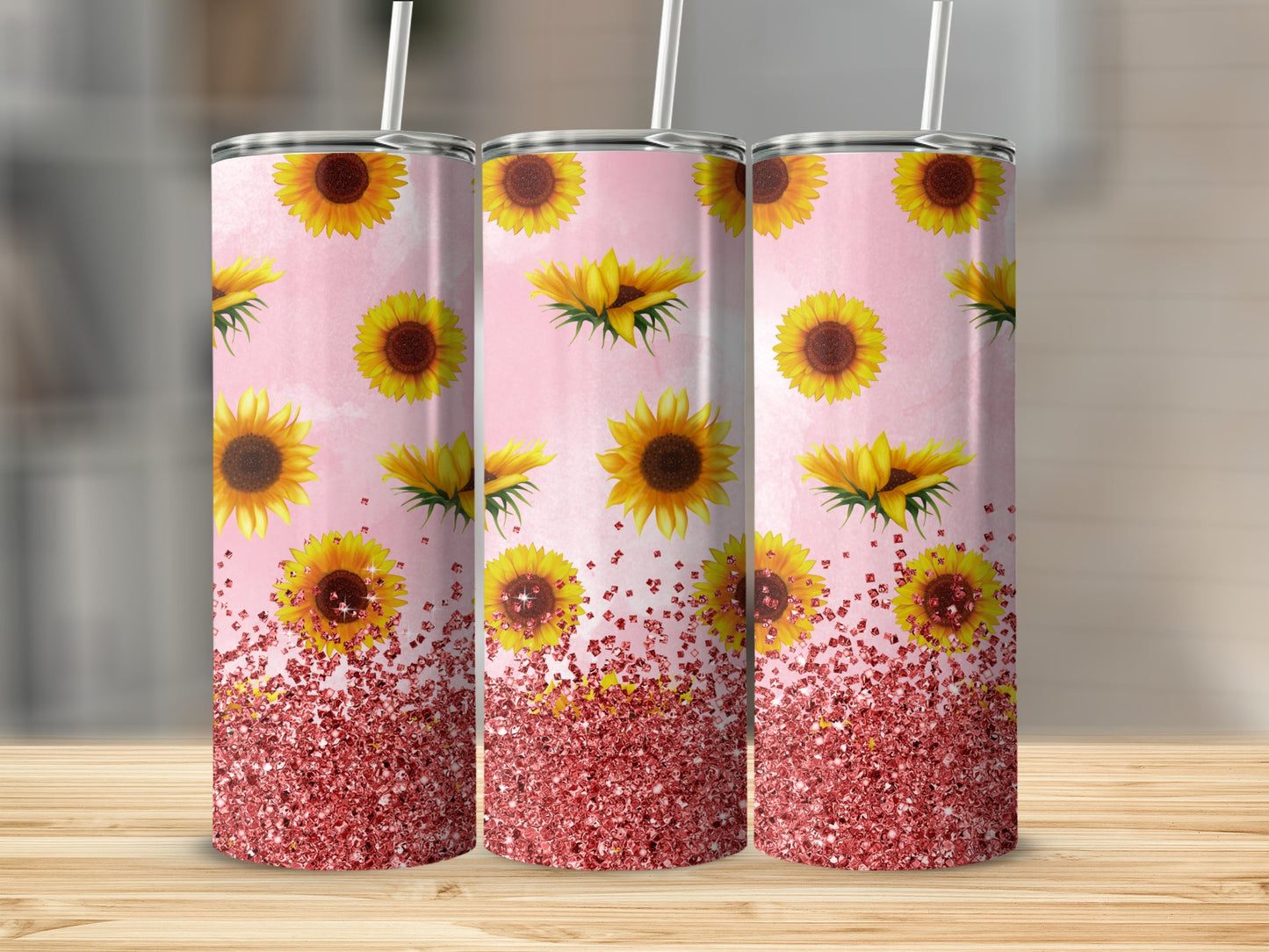 Three tumblers with sunflowers and pink glitter on a wooden surface.