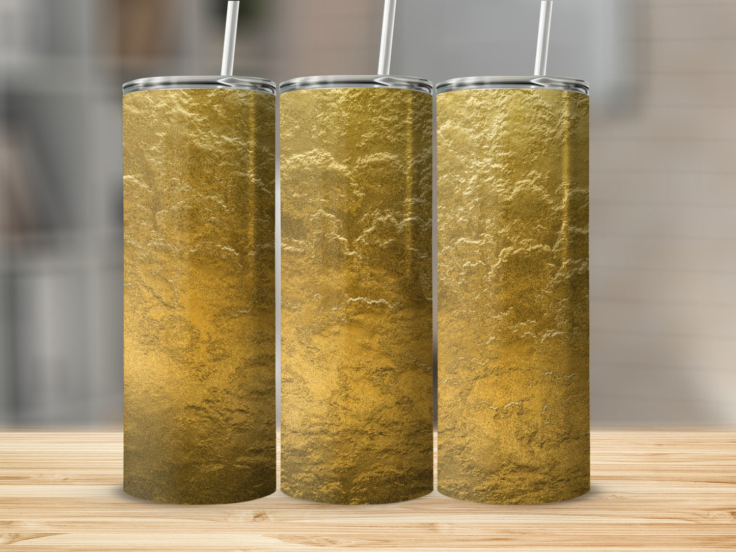 Three tumblers with gold metallic texture and white straws.