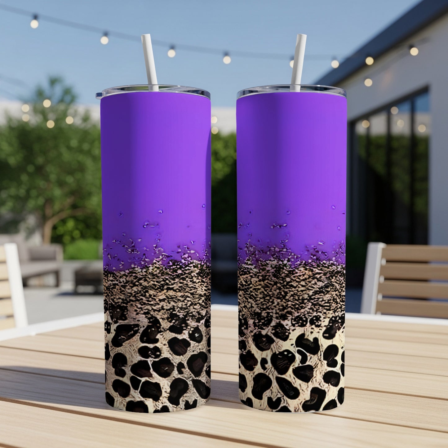 Two purple tumblers with leopard print and glitter design on outdoor table.