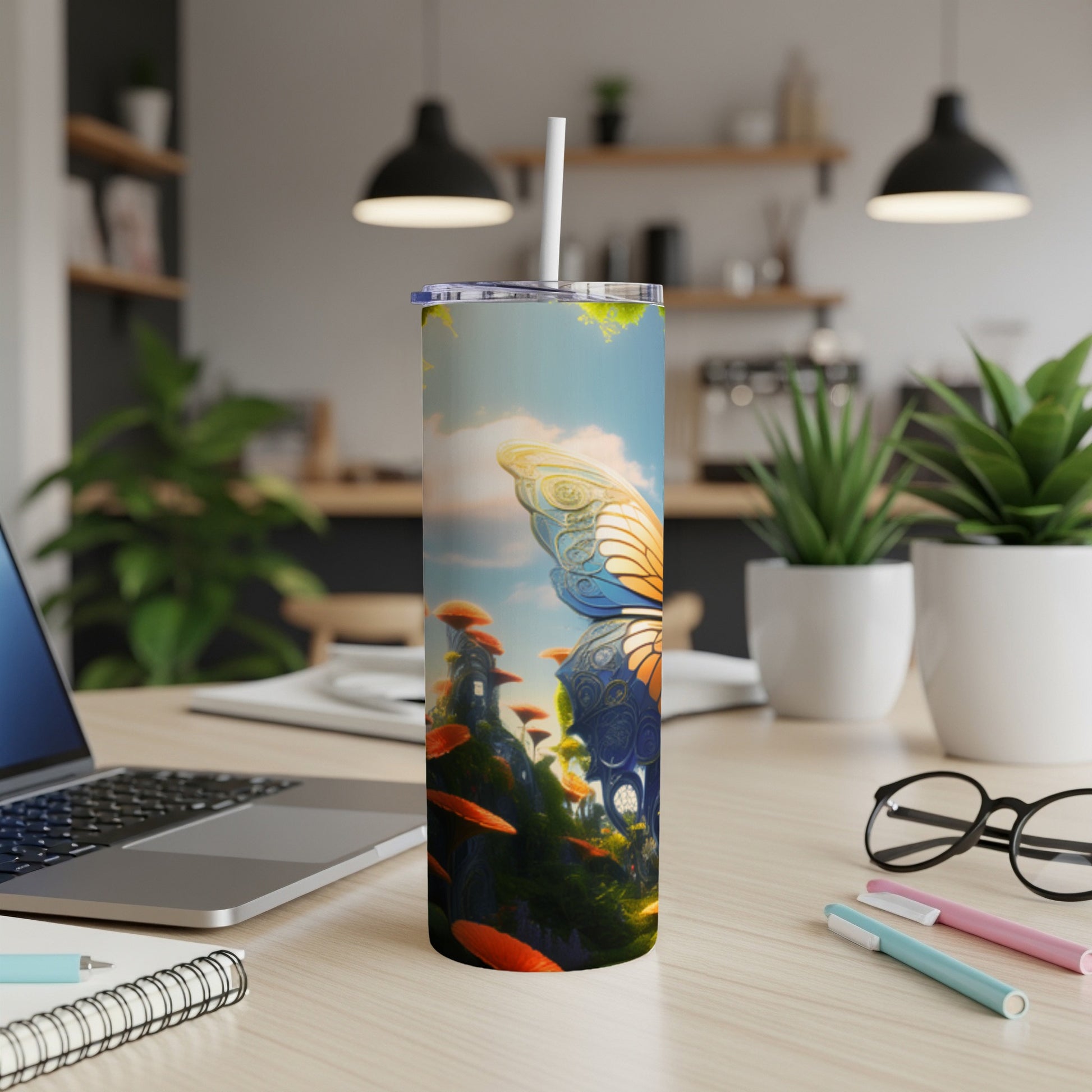 Tall tumbler with butterfly and mushroom design on desk with laptop.