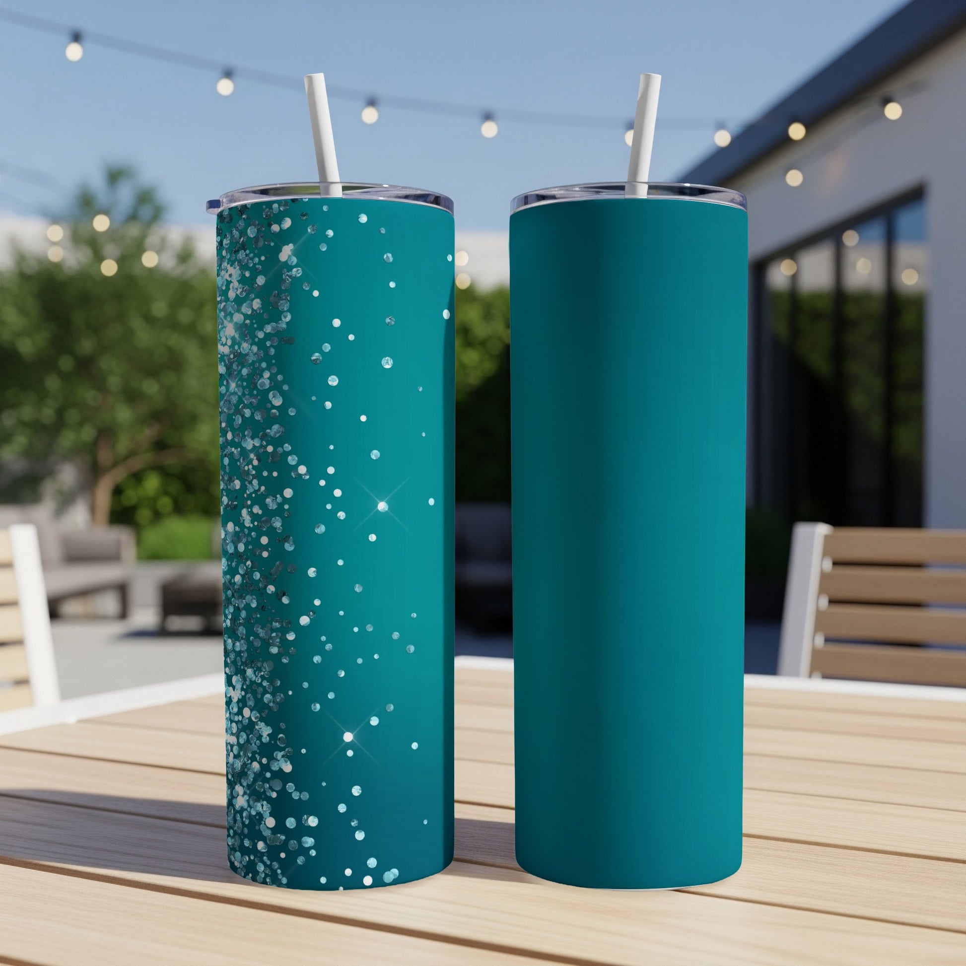 Two teal tumblers with straws on a wooden table, one with glittery accents.