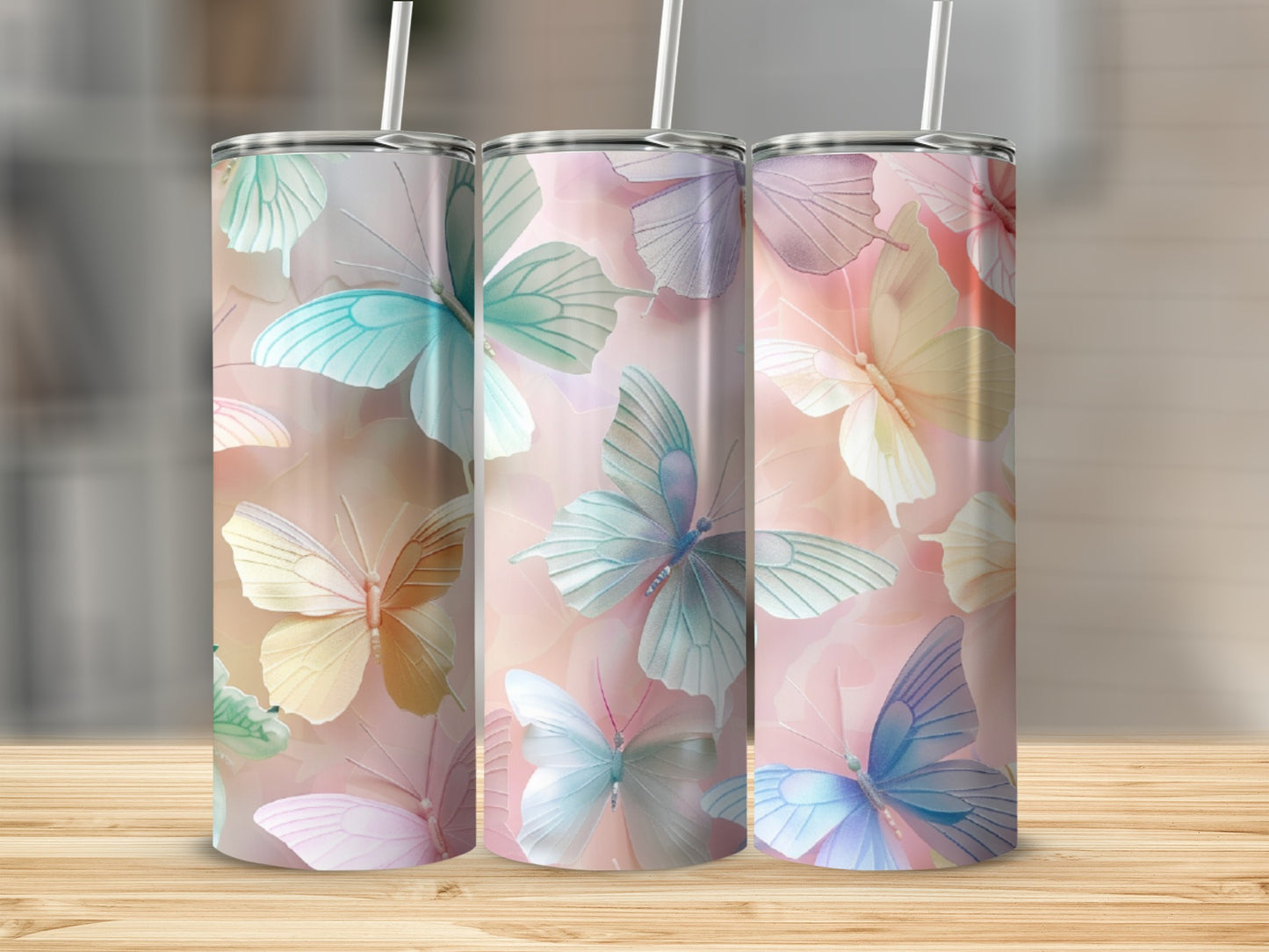Three tumblers with pastel butterfly designs stand on a wooden surface.