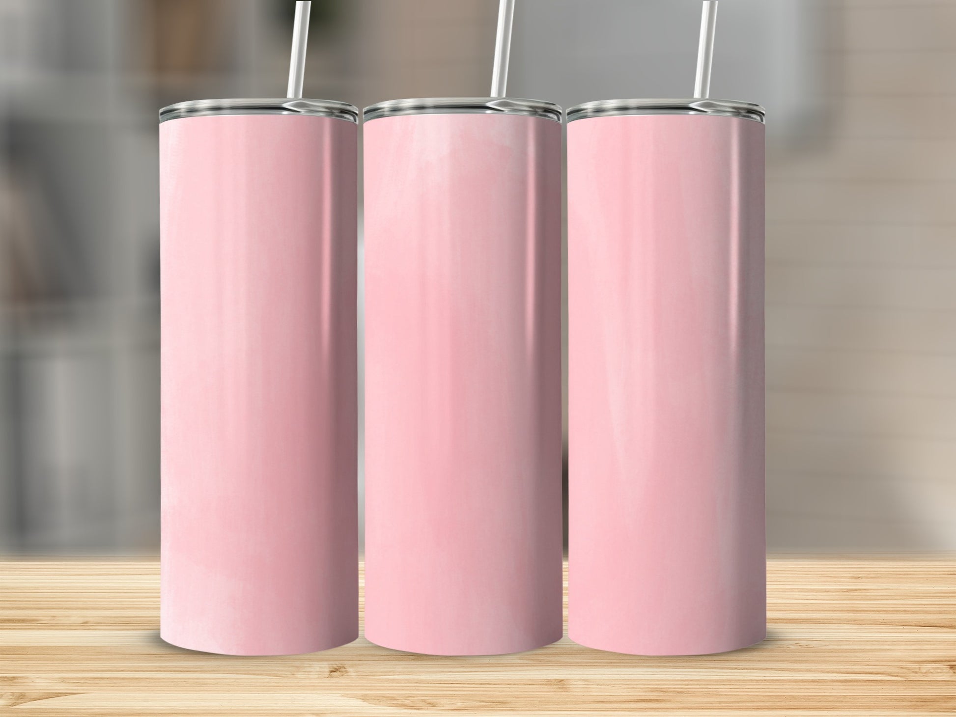Three pink tumblers with white straws stand on a wooden surface.