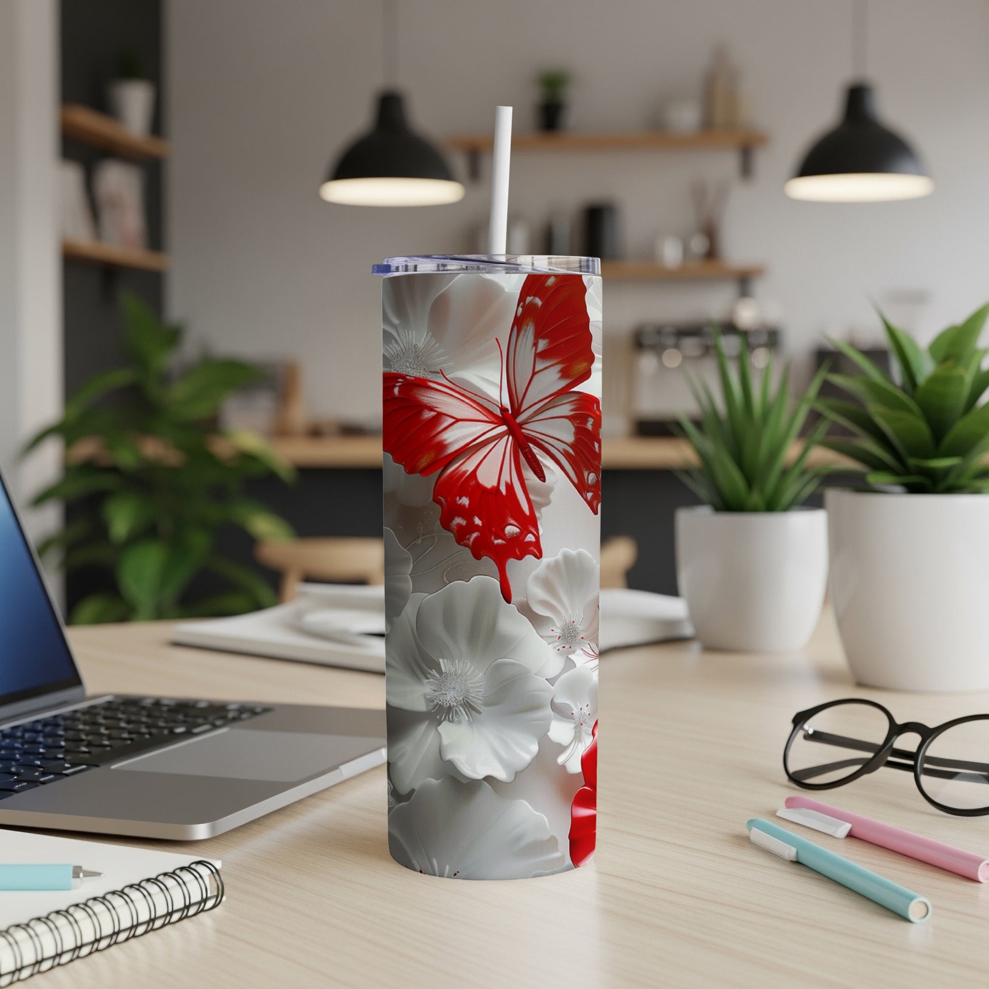 White tumbler with red butterfly and floral design on a desk.