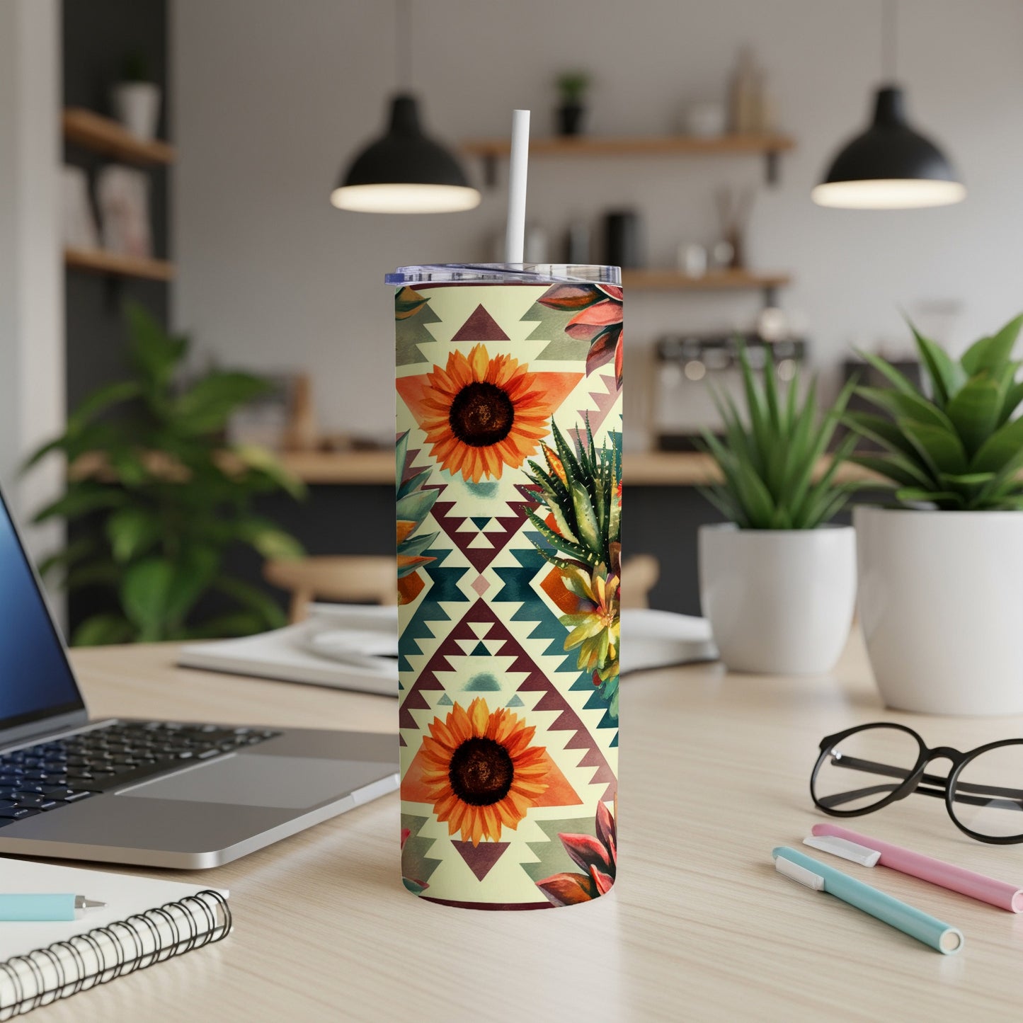 Sunflower and succulent patterned tumbler with a white straw on a desk.