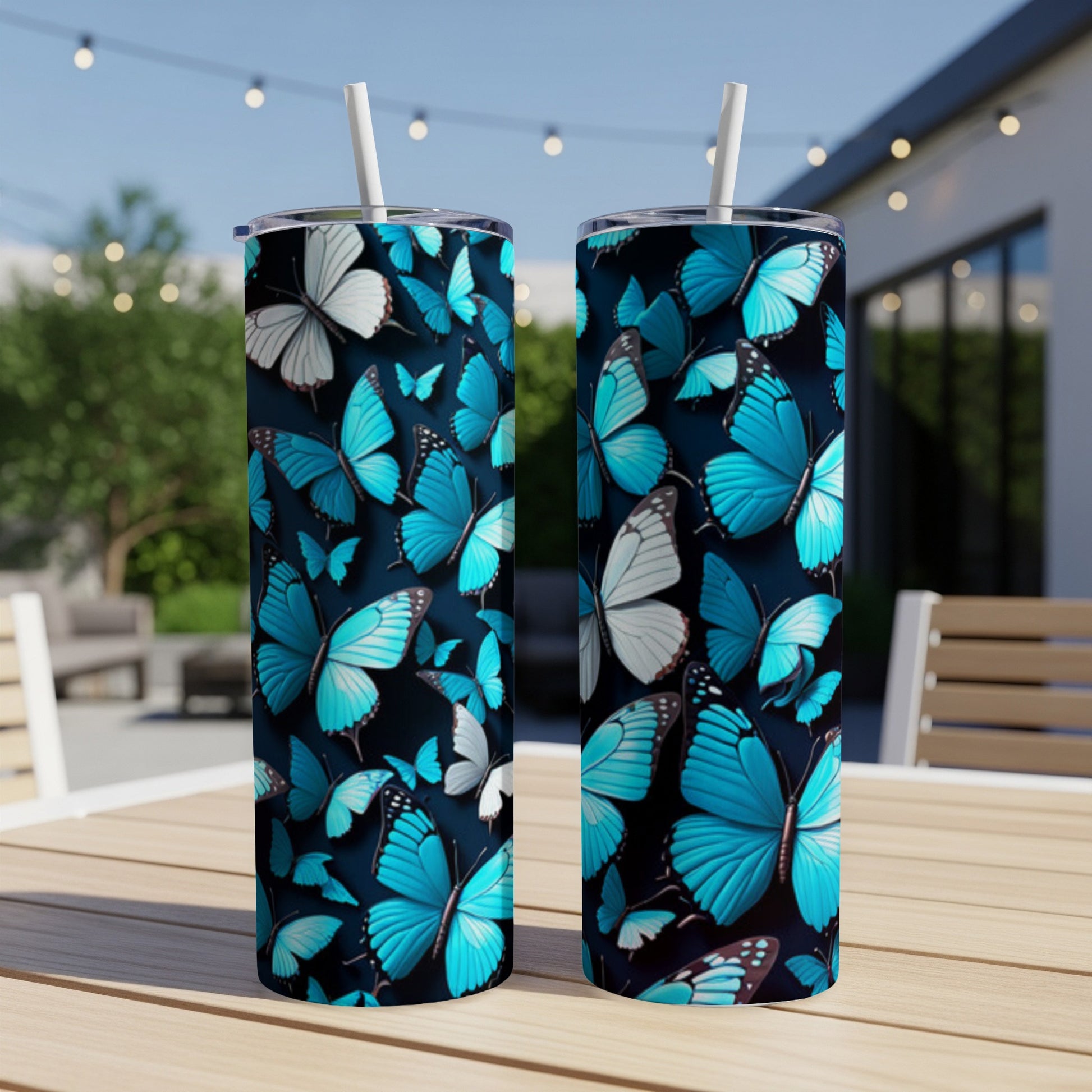Two blue butterfly print tumblers on a wooden table with a blurred outdoor background.