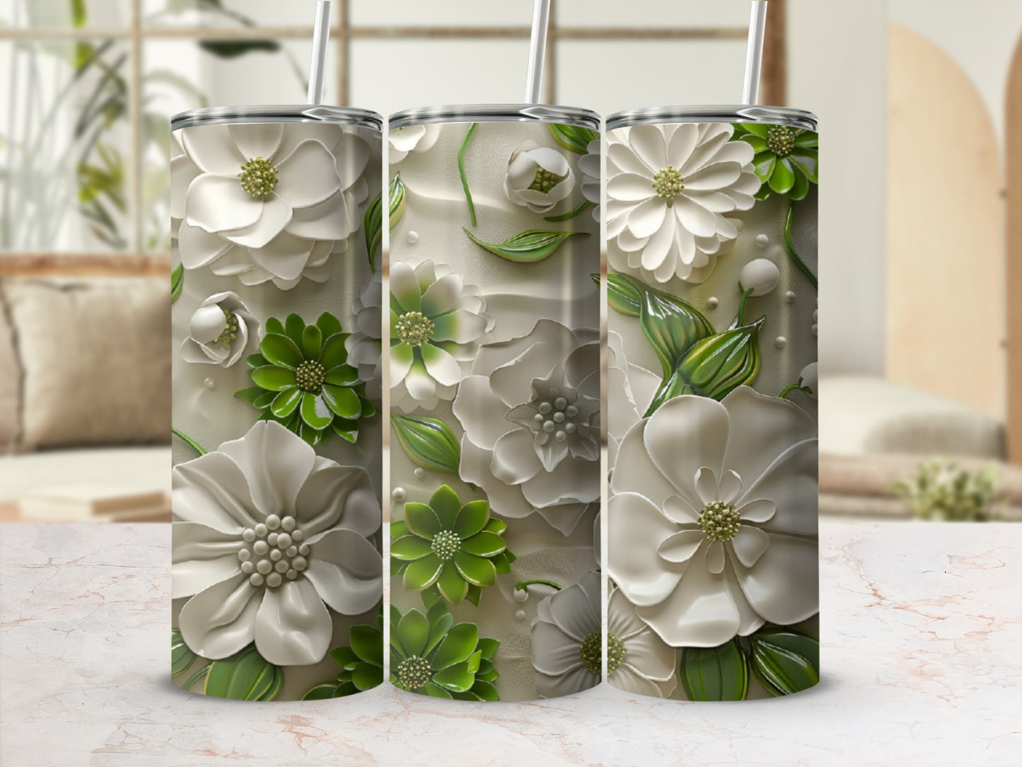 Three white and green floral tumblers with straws on a patterned surface.