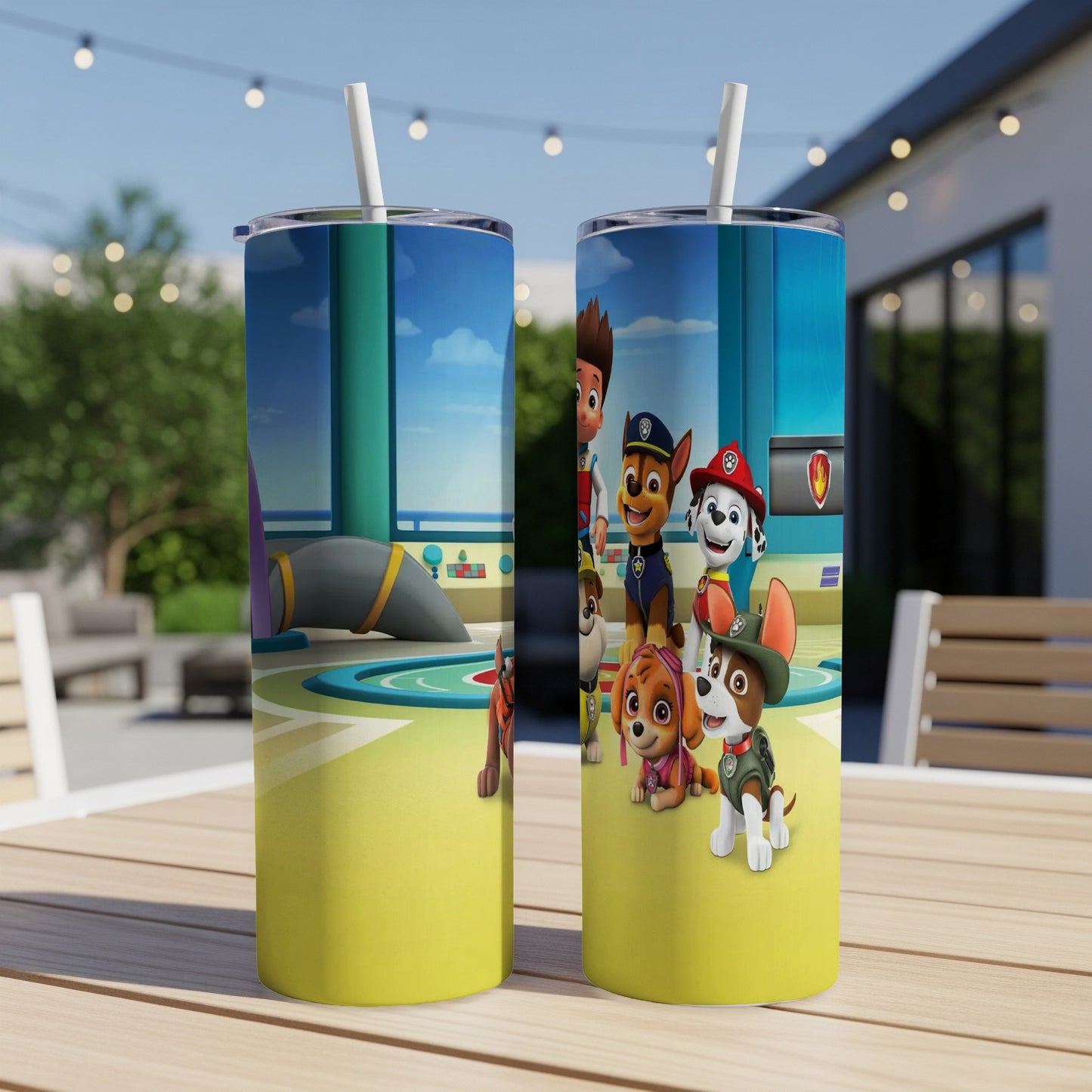 Two Paw Patrol tumblers with characters on a wooden table outdoors.