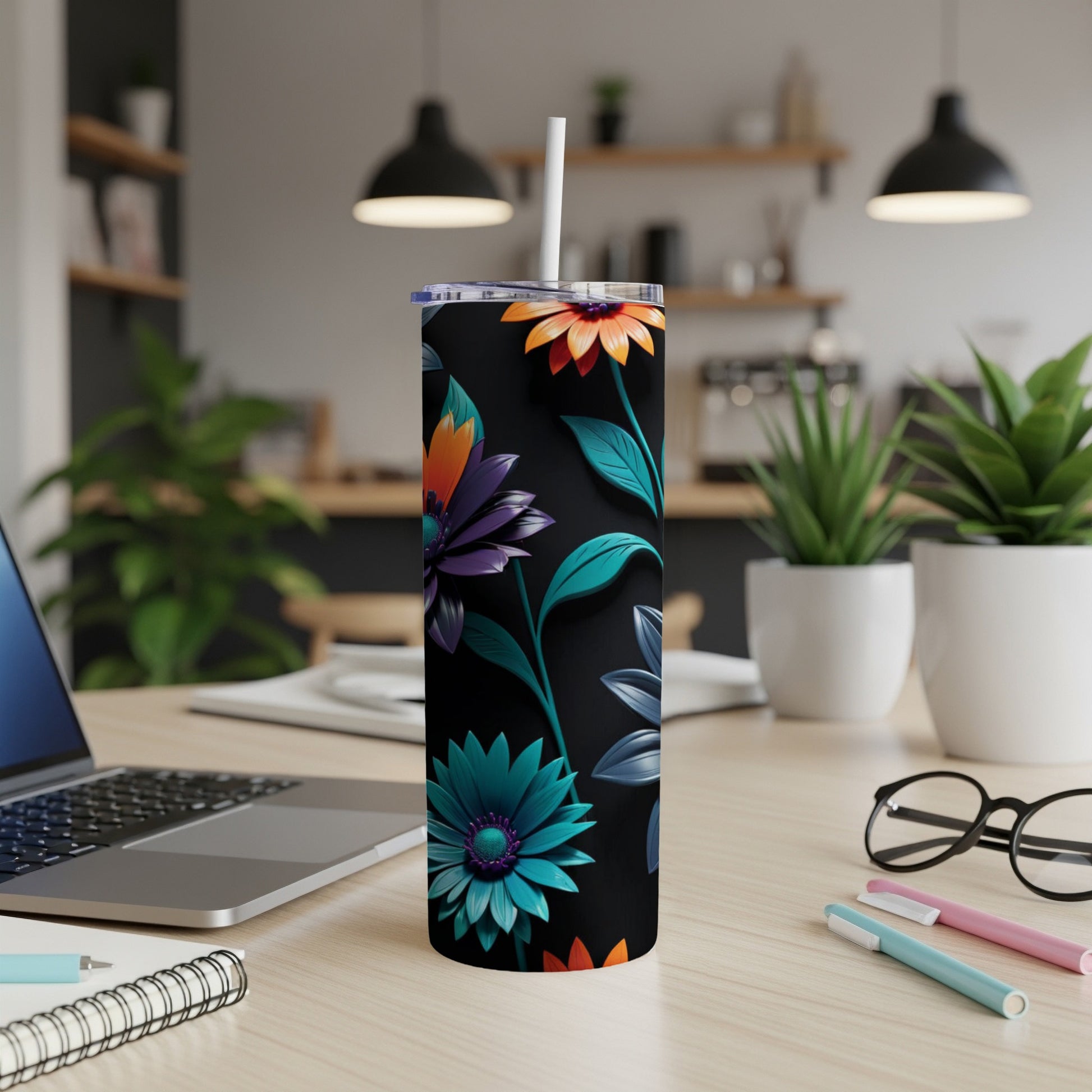 Black tumbler with vibrant floral design, white straw, on desk with laptop.