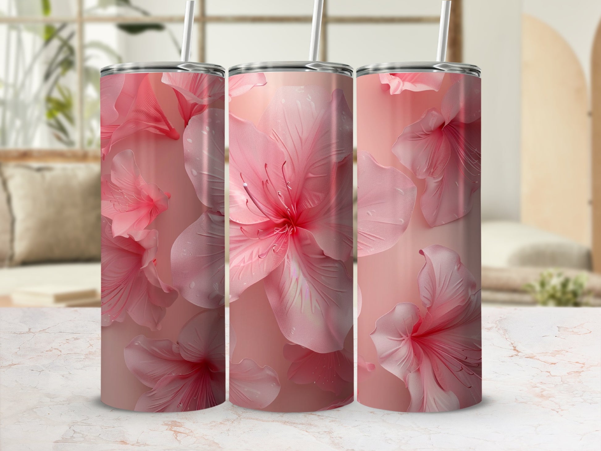 Three tall pink floral tumblers with straws on a marble surface.