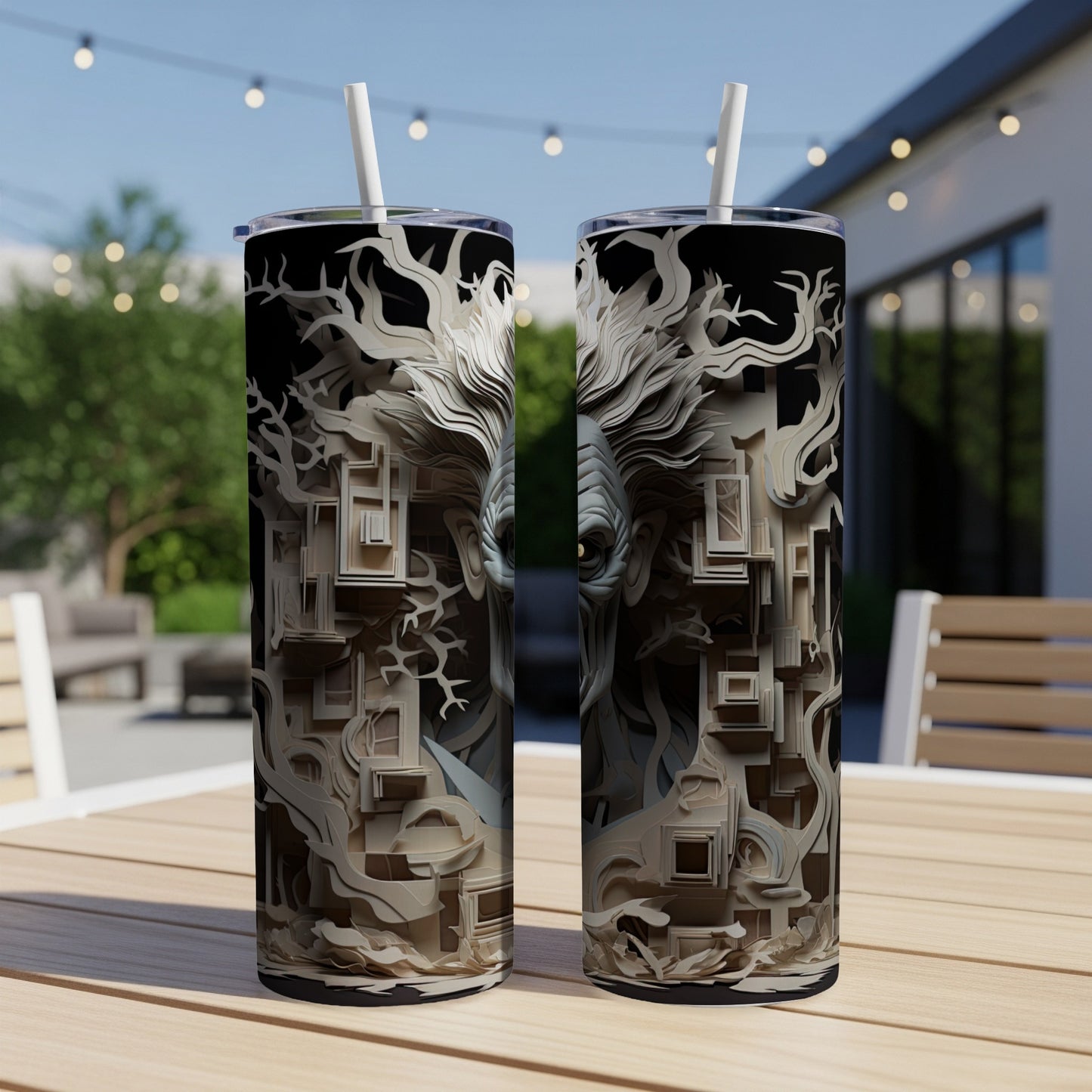 Two tumblers with abstract white and black tree and face designs, placed outdoors.