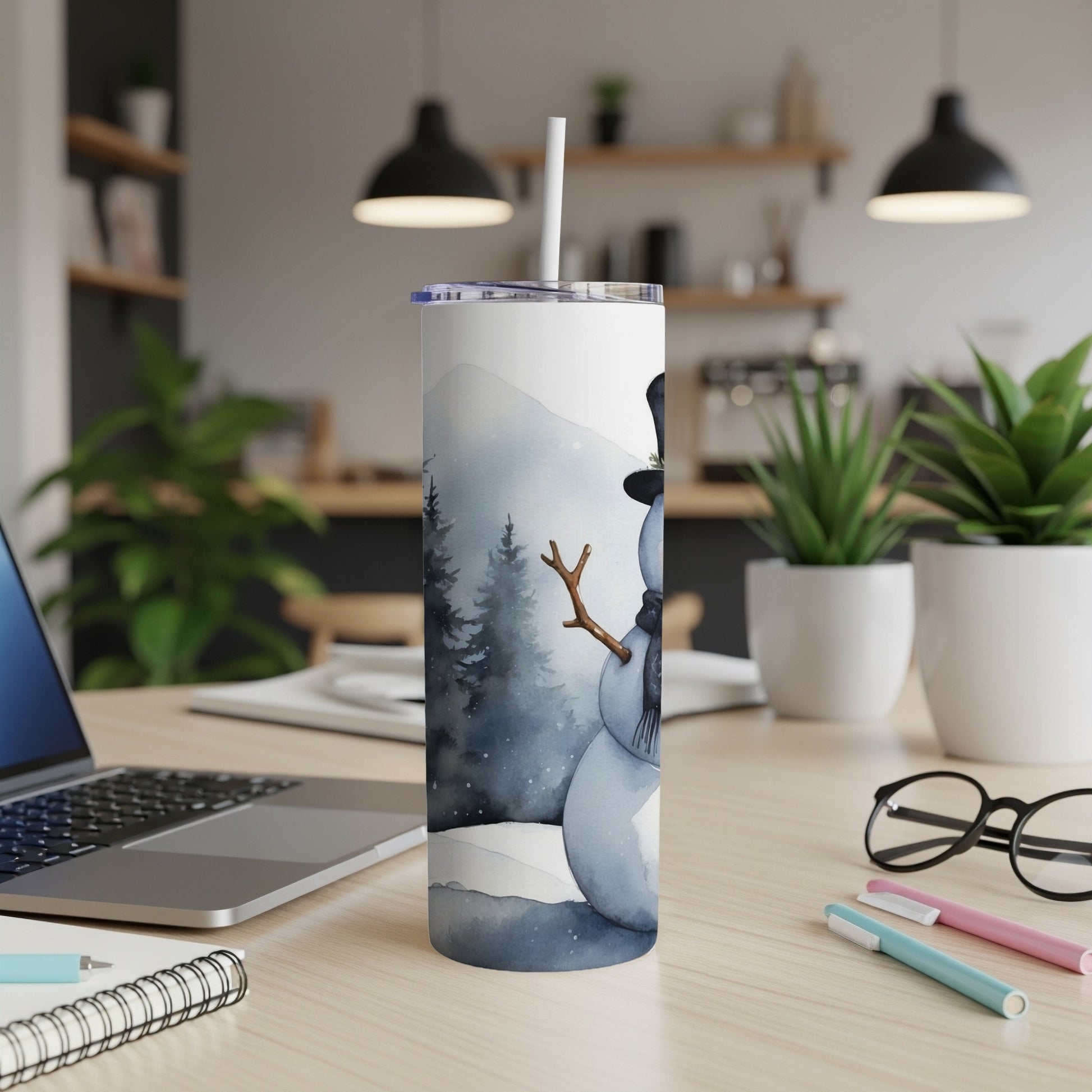 White tumbler with watercolor snowman design on desk.