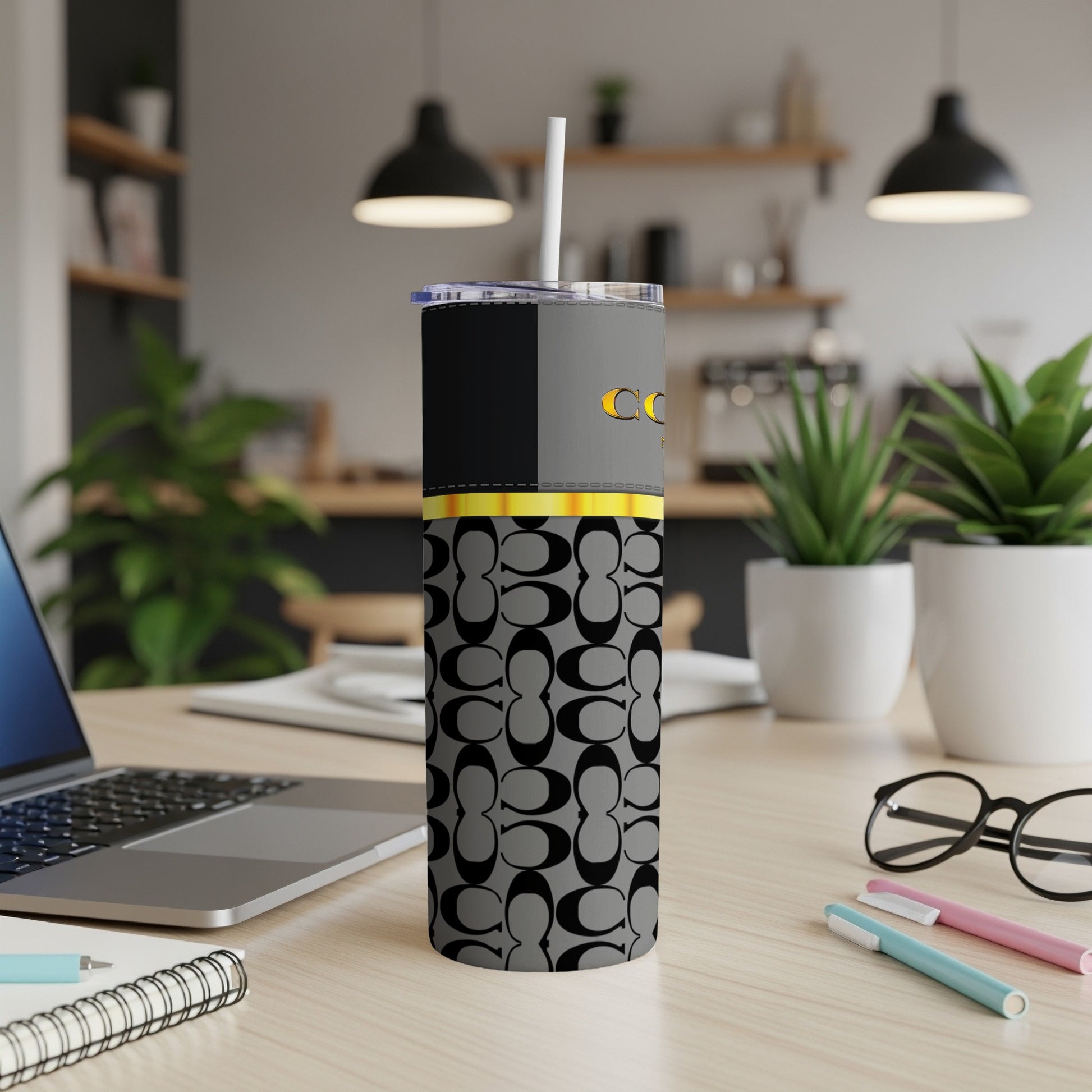 A grey tumbler with an all-over black C logo pattern and gold accents.