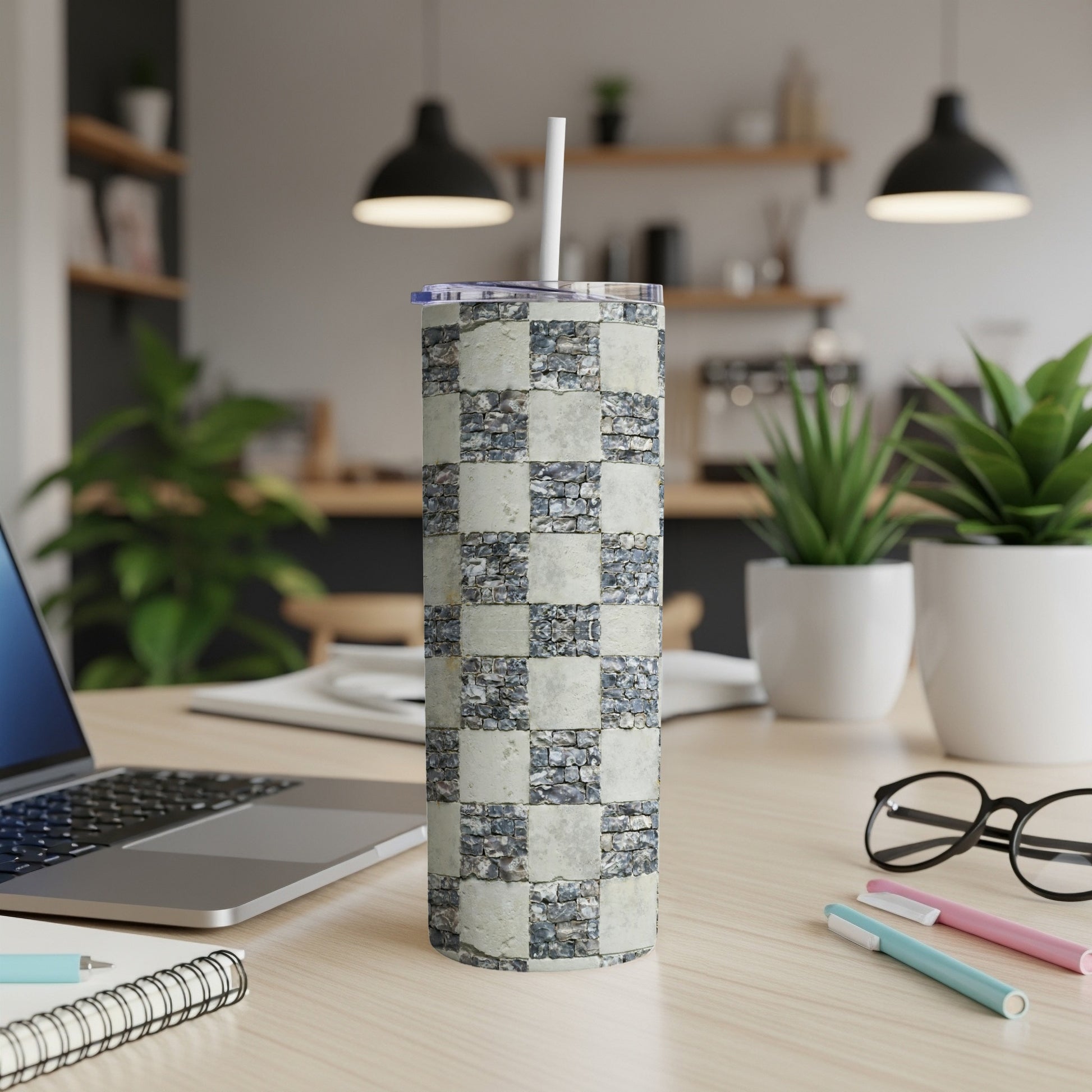 Checkerboard stone pattern tumbler with straw on a desk.