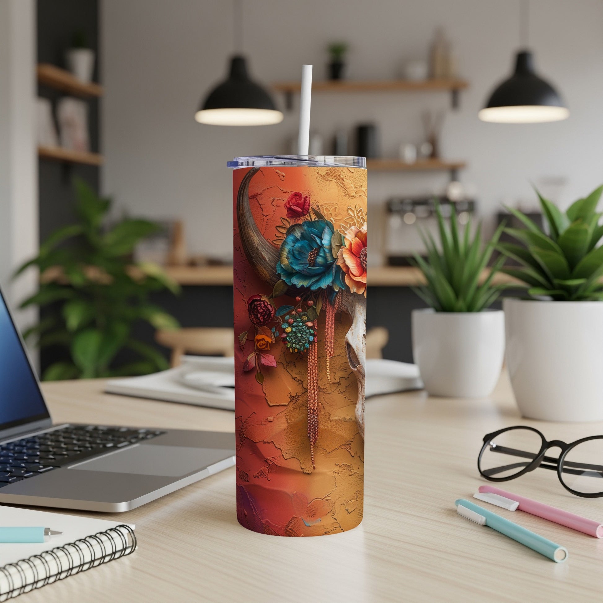 Tumbler with cow skull adorned with colorful flowers against an orange textured background.