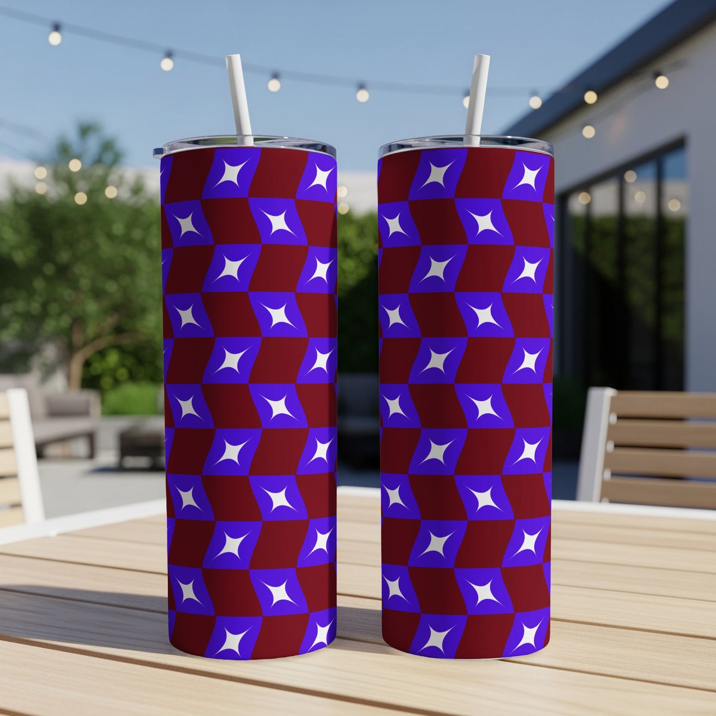 Two tumblers with a maroon and blue star pattern and white straws sit on a table.