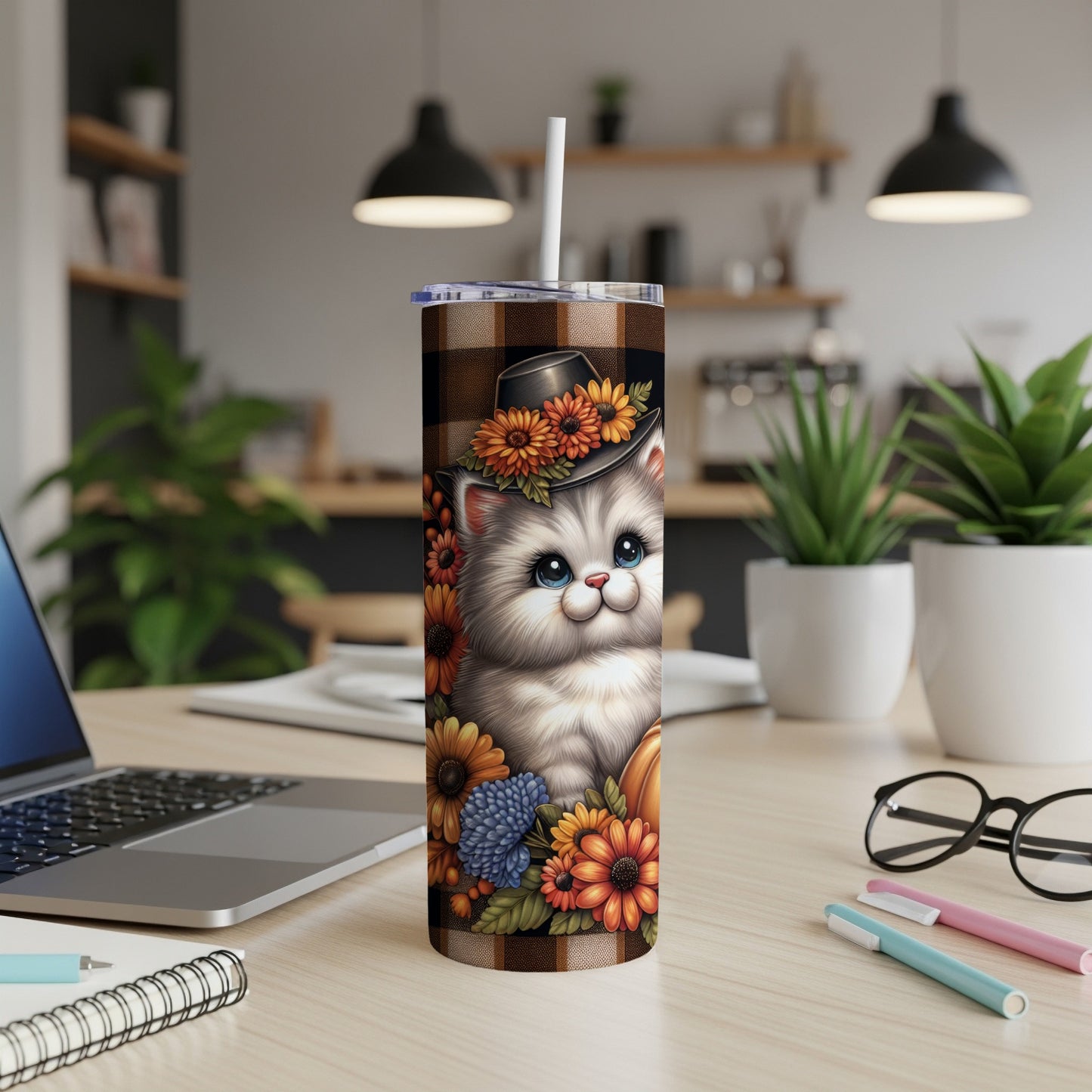 White fluffy kitten with floral accents wearing a plaid hat on a tumbler.