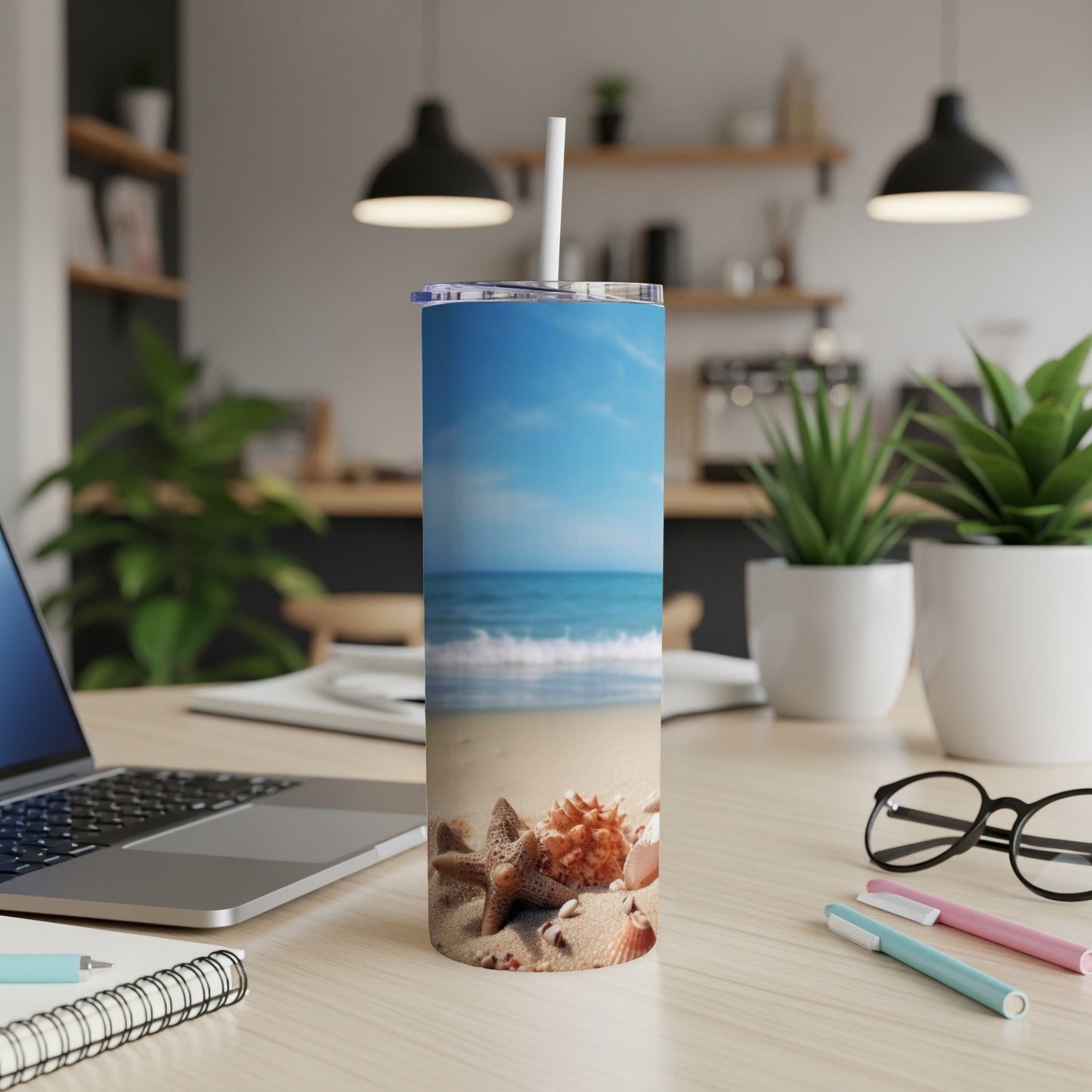 Beach scene tumbler with starfish and shells on a desk.