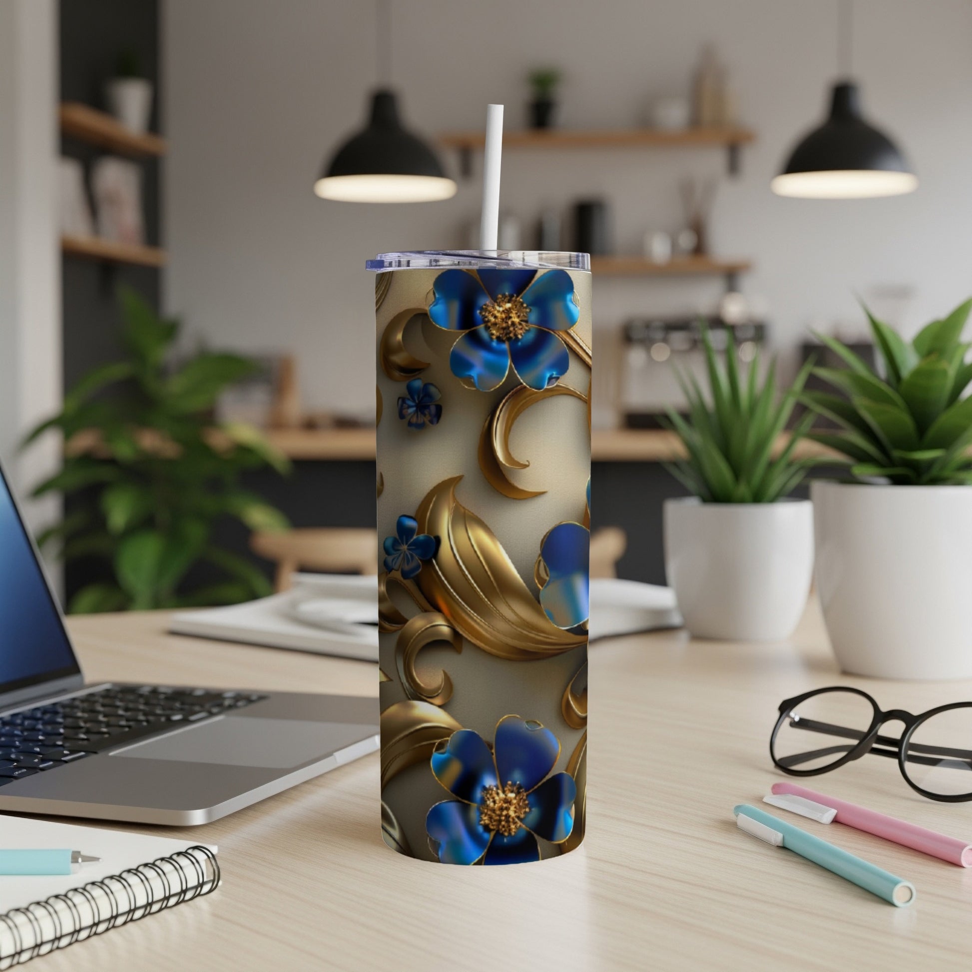 Blue and gold floral patterned tumbler with straw on desk.