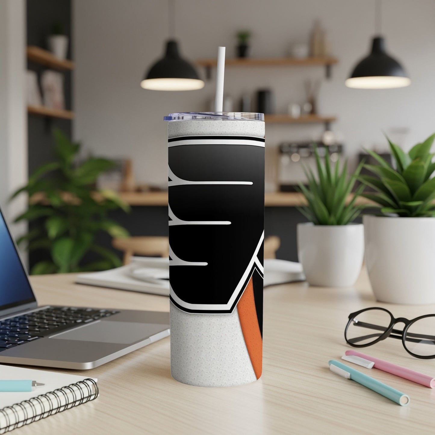 Tumbler with Philadelphia Flyers logo and straw on desk with laptop and glasses.