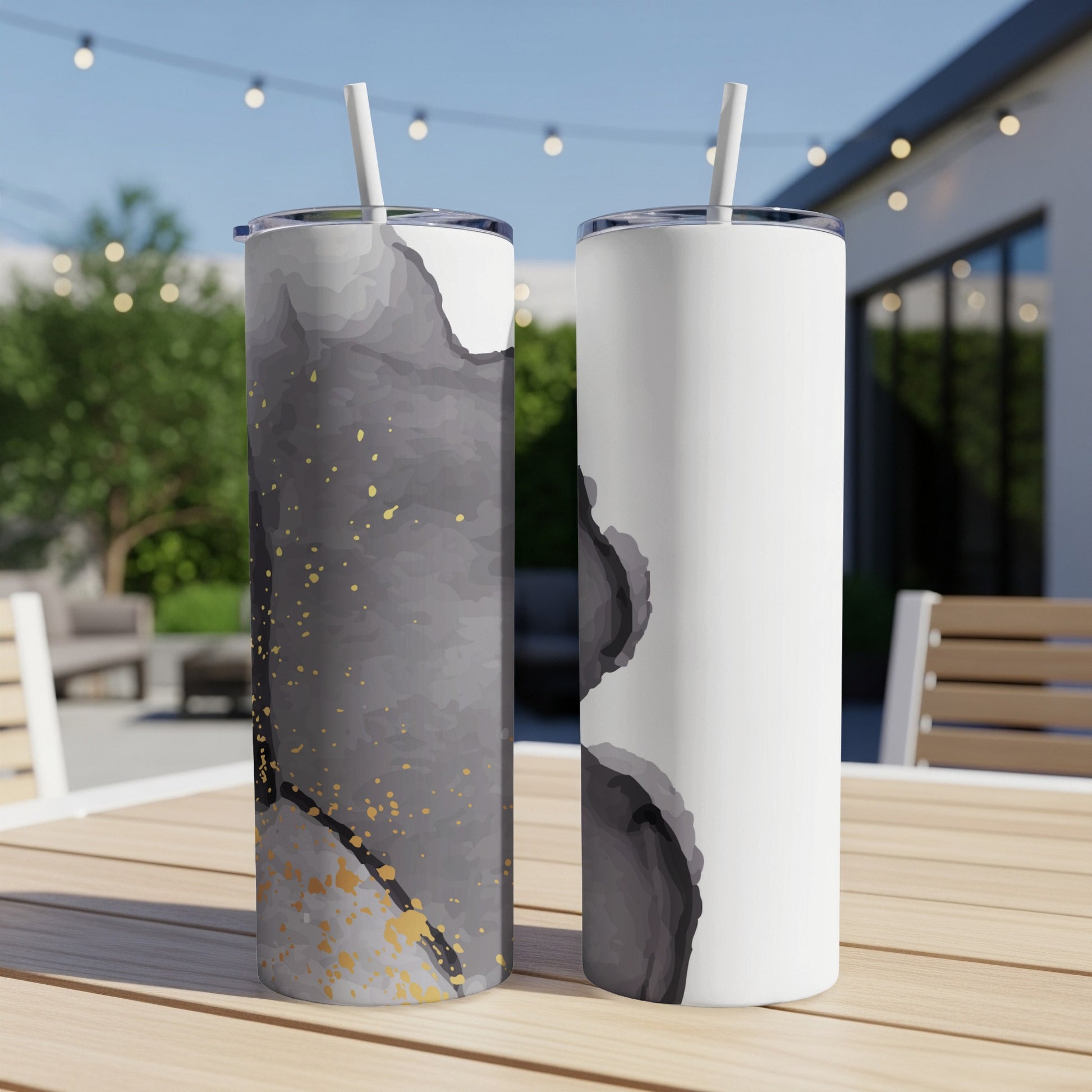 Two tumblers on a table, one dark abstract design, one white abstract design.