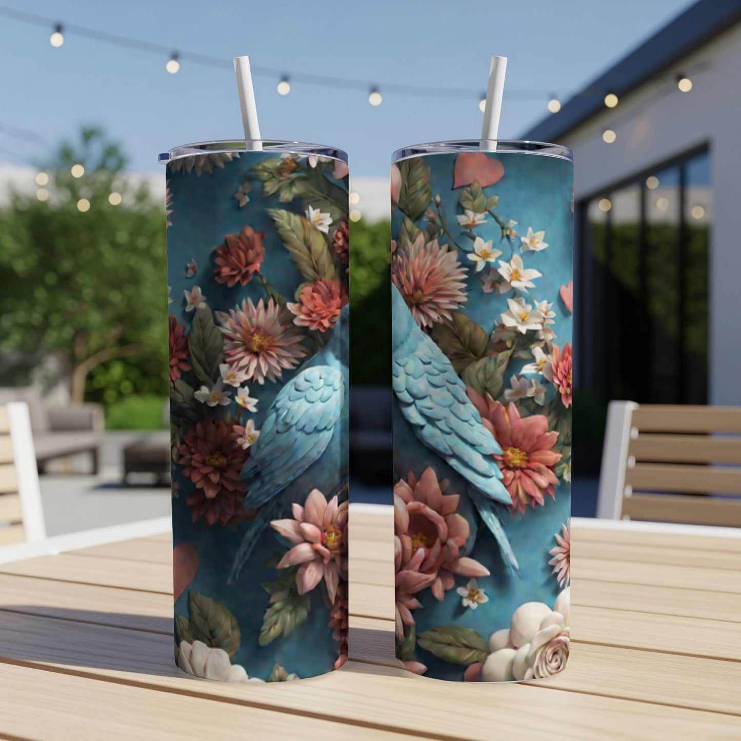 Two blue parrots sit among colorful flowers on a teal patterned skinny tumbler.