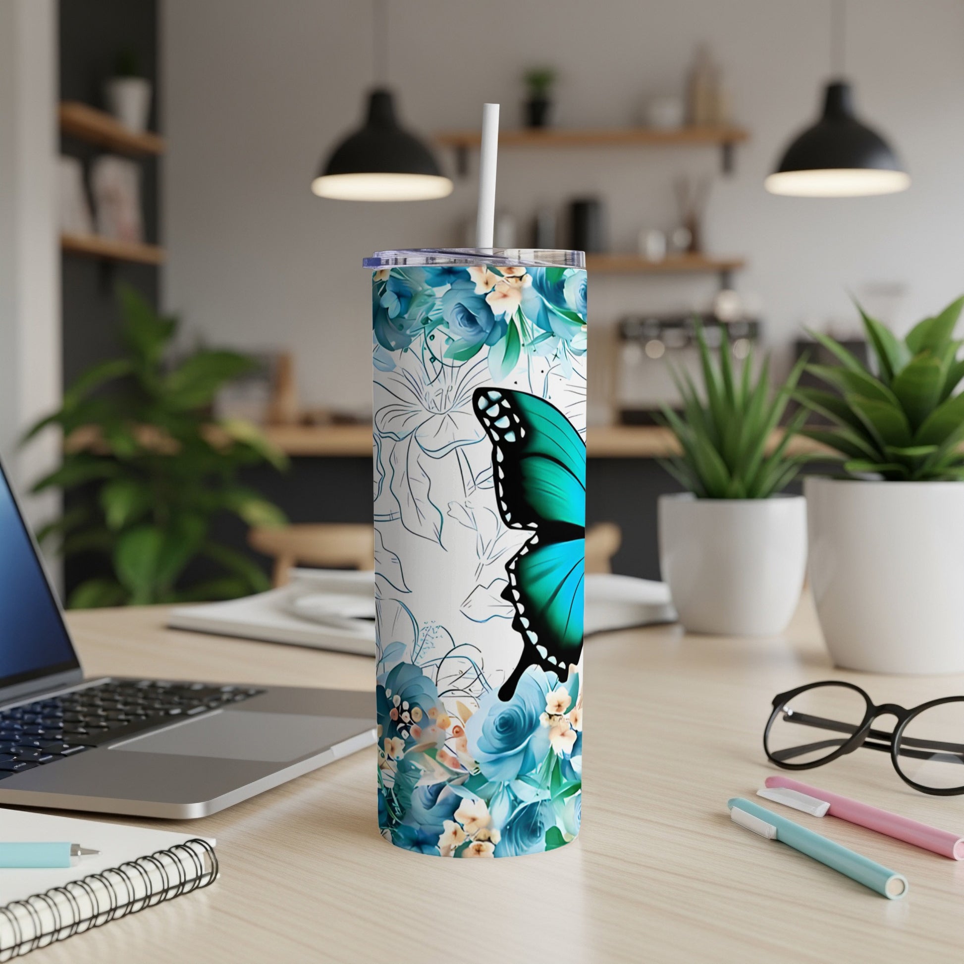 Blue butterfly and floral print skinny tumbler on desk with laptop and pens.