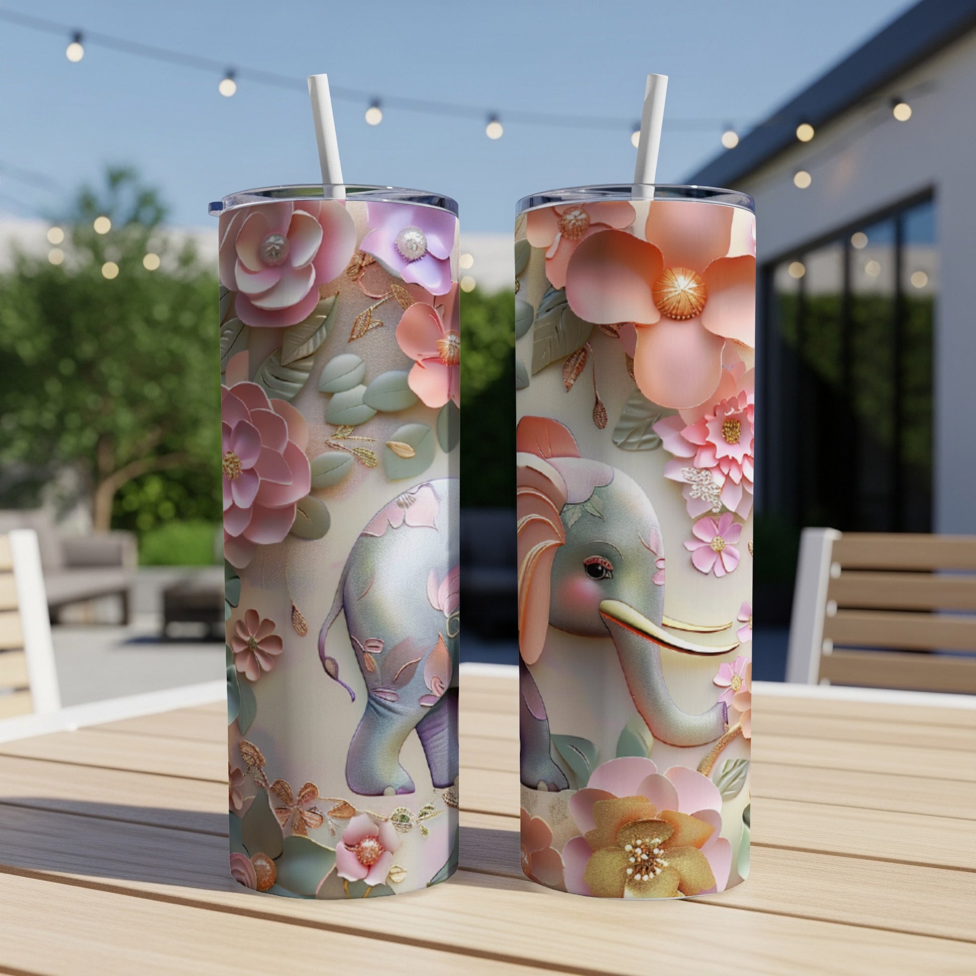 Pink floral elephant tumbler with straw on outdoor table.
