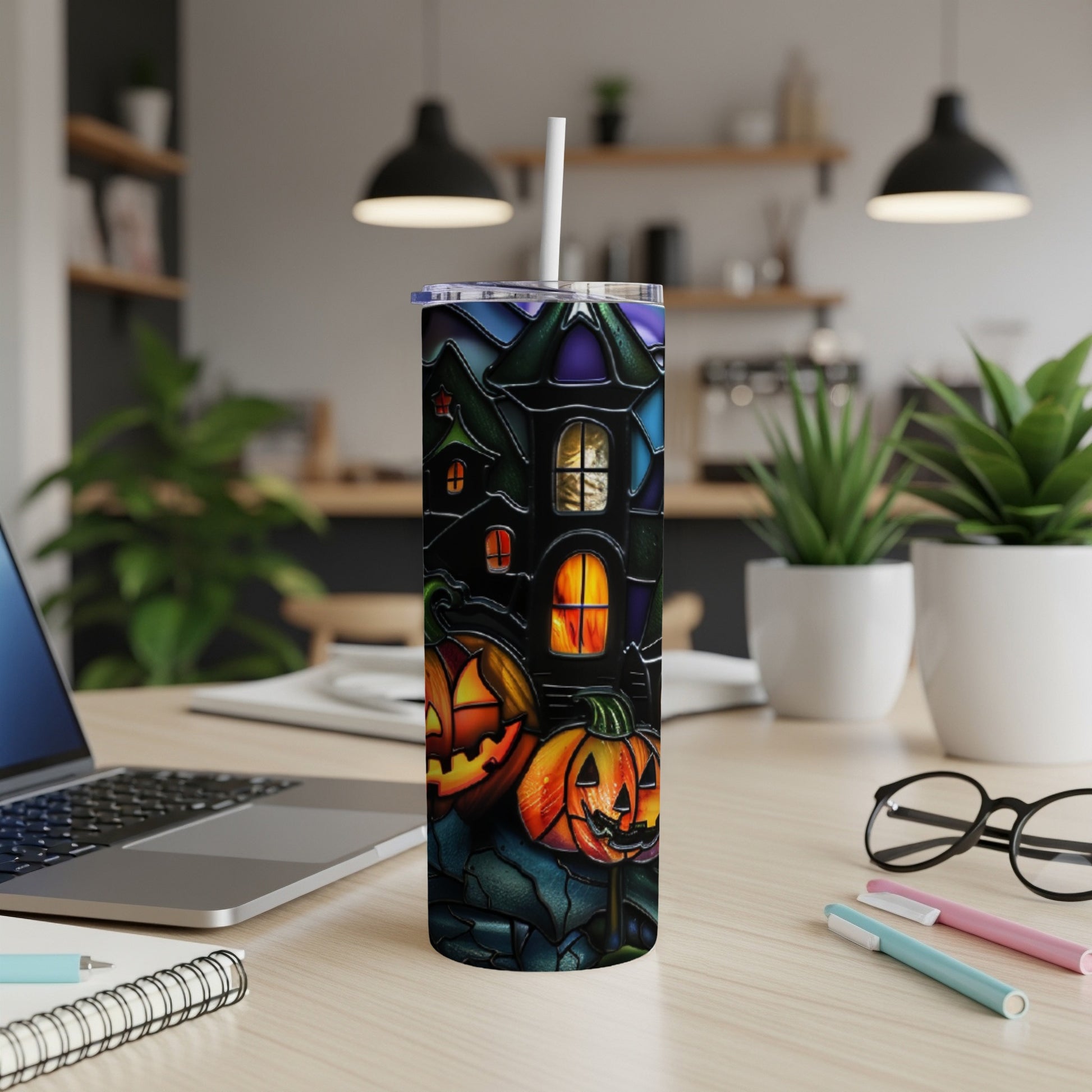 Halloween tumbler with pumpkins and haunted house on a desk.