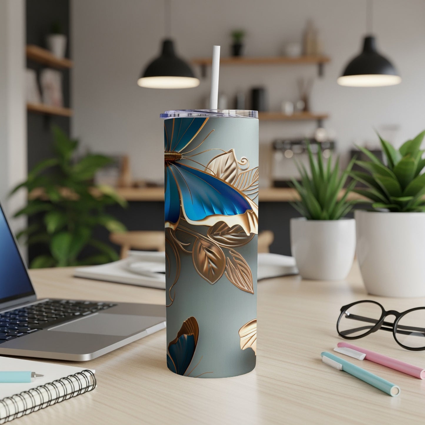 Tumbler with blue butterfly and gold leaf design on a desk.