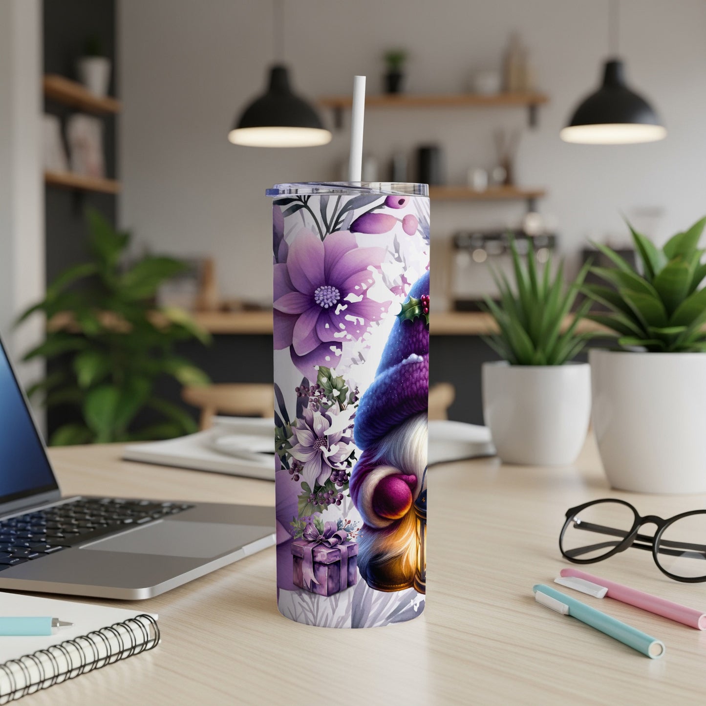Purple gnome with floral accents on a tumbler, on a desk with laptop.