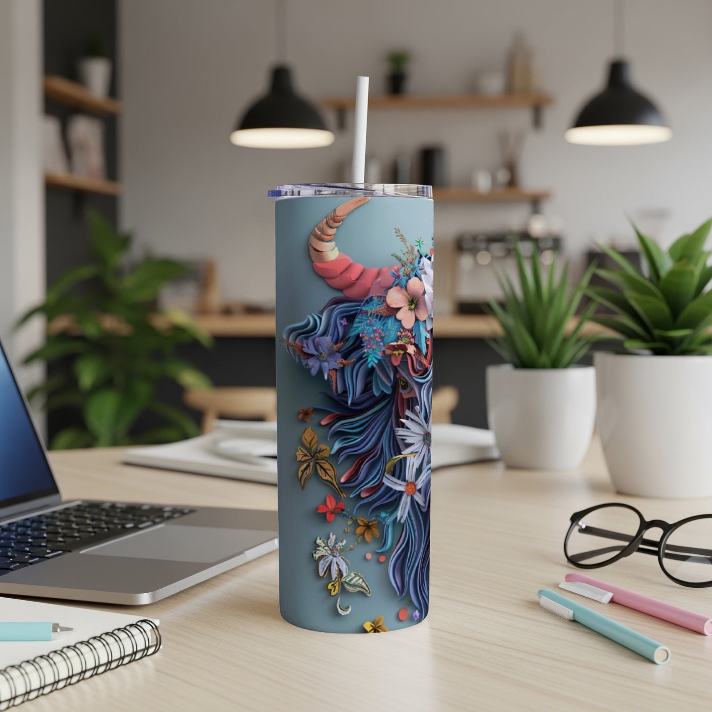 Tall tumbler with a blue and purple floral bull design on a wooden desk.