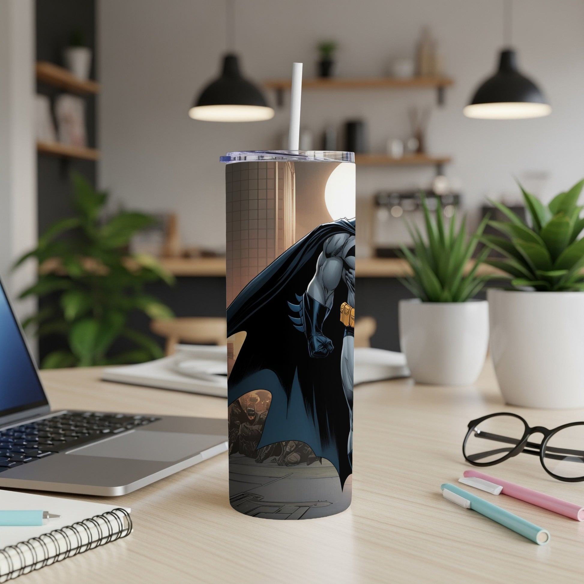 Batman illustration on a white tumbler with a straw, on a desk.
