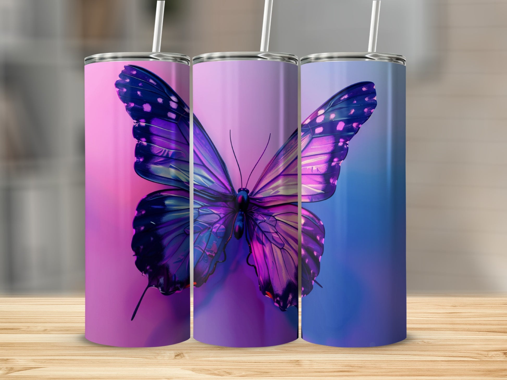 Three tumblers with iridescent butterfly designs on a wooden surface.