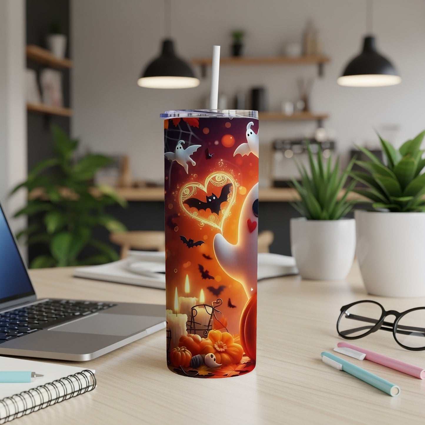 Halloween tumbler with ghosts, bats, pumpkins, and candles on a desk.