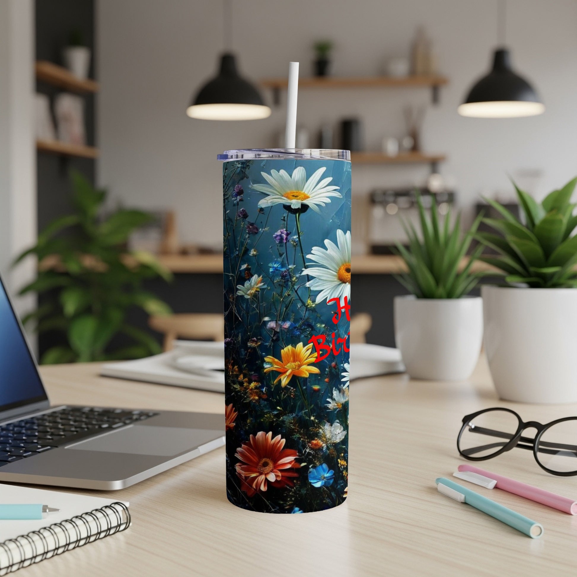Tall tumbler with daisies and red "Happy Birthday" text on desk.