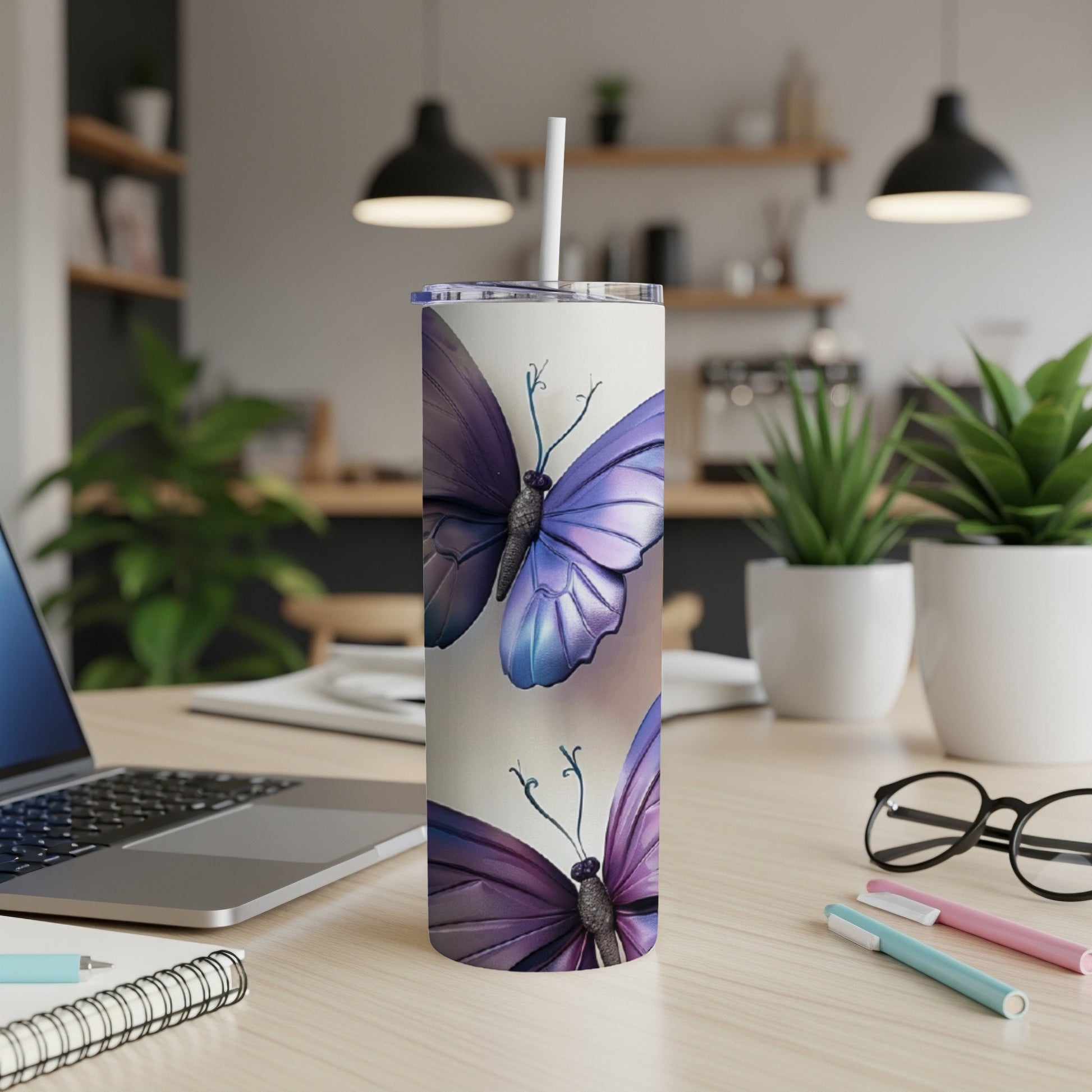 Tall tumbler with purple butterflies on a desk with a laptop.
