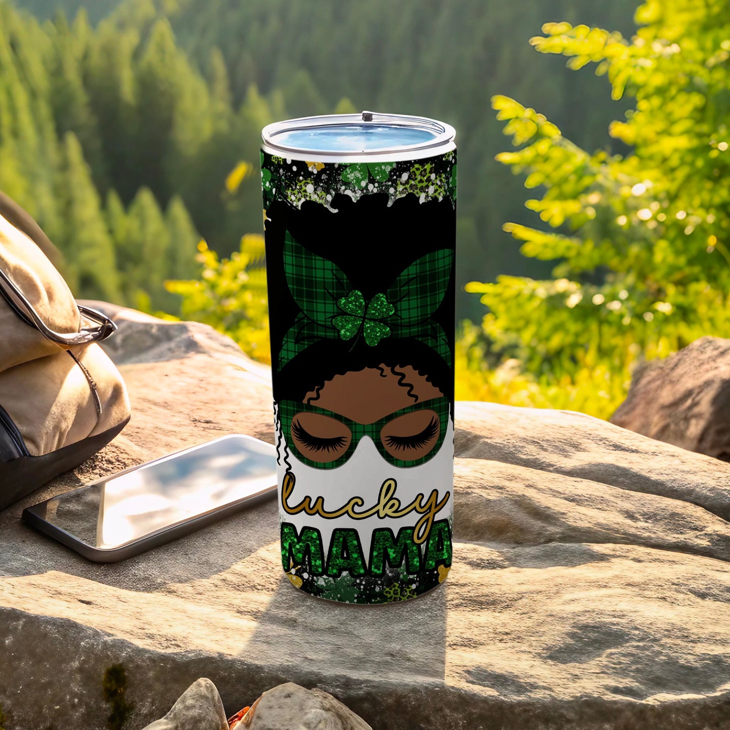 Green plaid "Lucky Mama" tumbler with curly hair and glasses on rock.