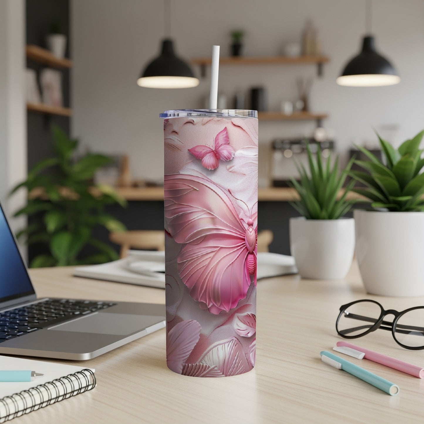 Pink butterfly tumbler with straw on a desk.