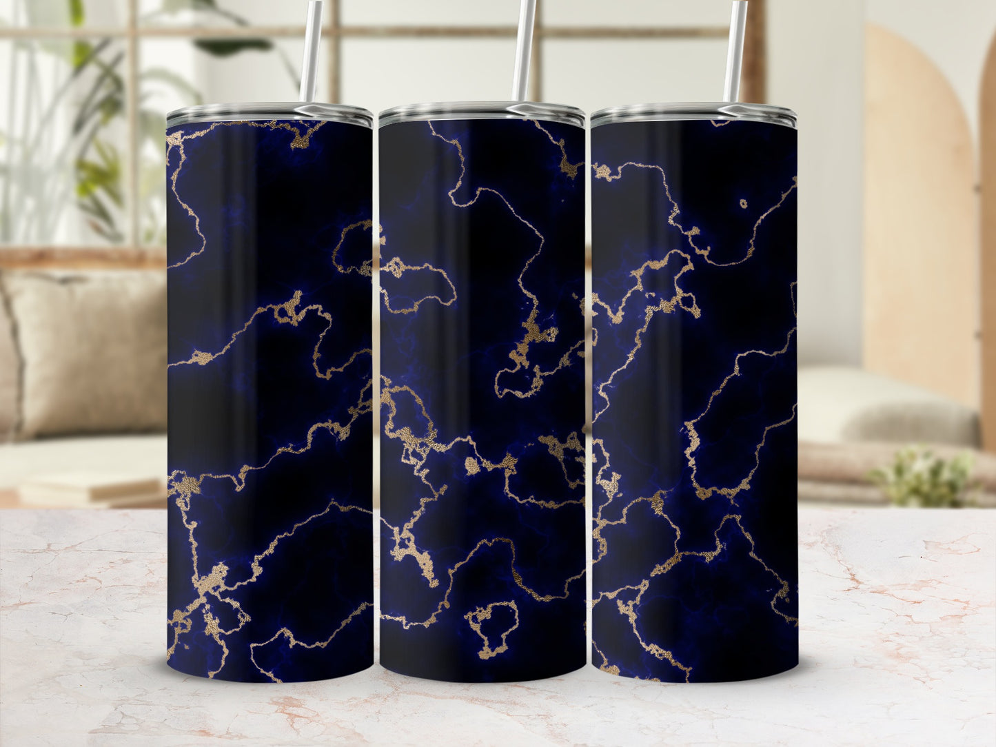 Three dark blue tumblers with gold marble pattern and straws.